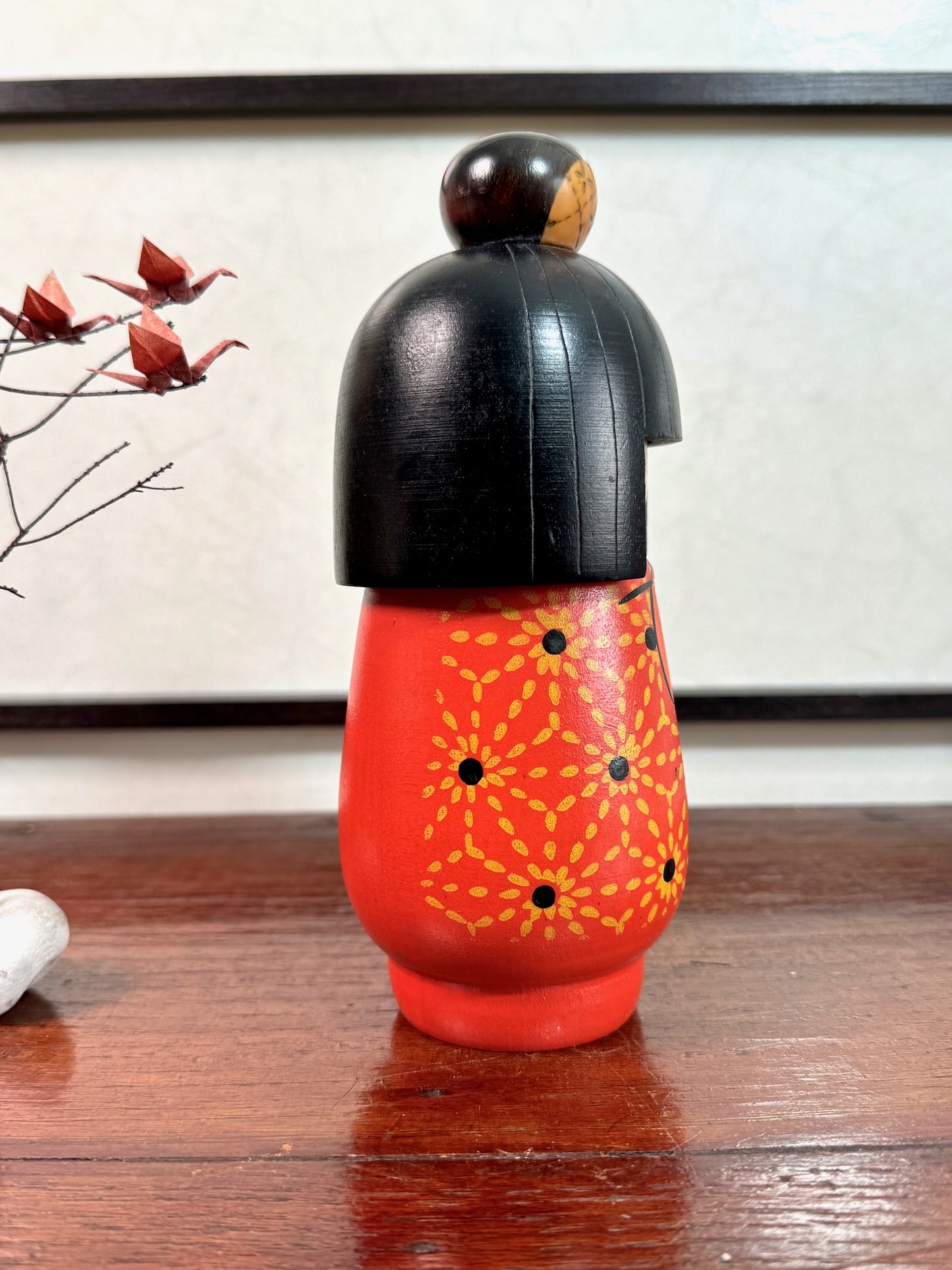 kokeshi de Kazuo tamikazawa, kimono rouge motif fleurs stylisées, cheveux noirs avec chignon pyrogravé, profil droit