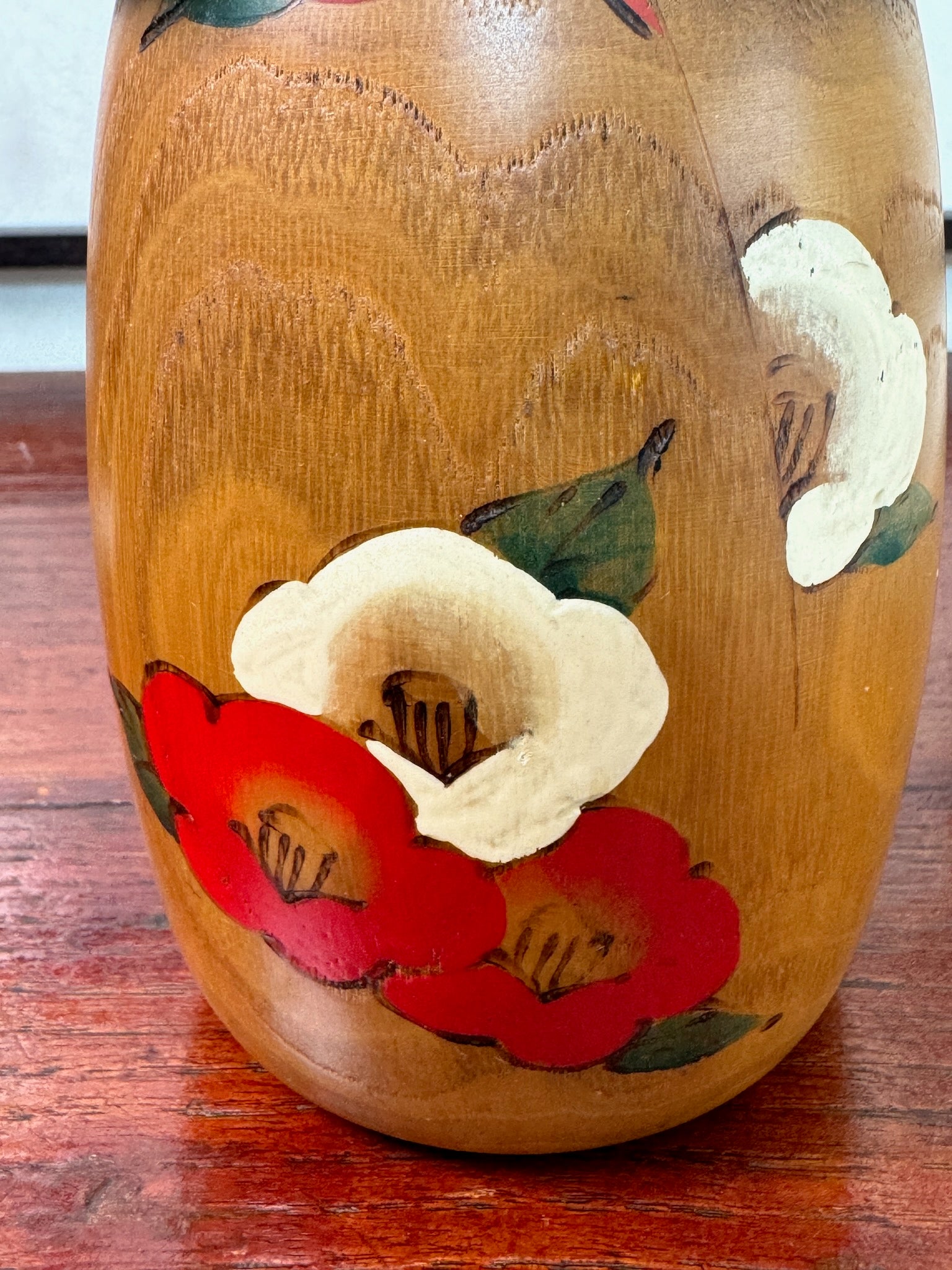 kokeshi poupée japonaise en bois de Usaburo, décor fleurs de camélia rouge et blanc sur bois blond, gros plan sur 2 fleurs rouges et une blanche