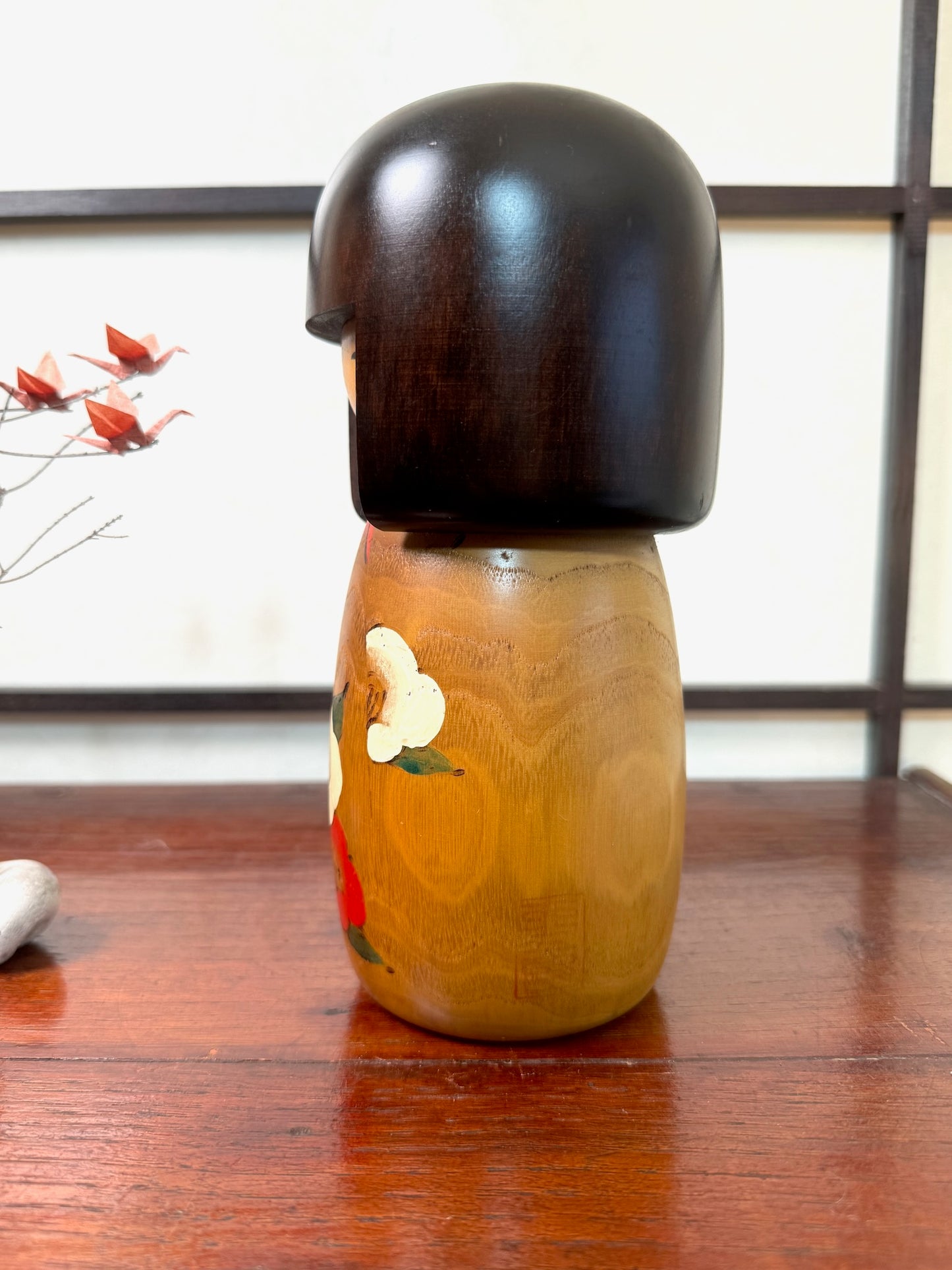 kokeshi poupée japonaise en bois de Usaburo, décor fleurs de camélia rouge et blanc sur bois blond, coiffure brune au carré, visage clair et souriant, profil gauche