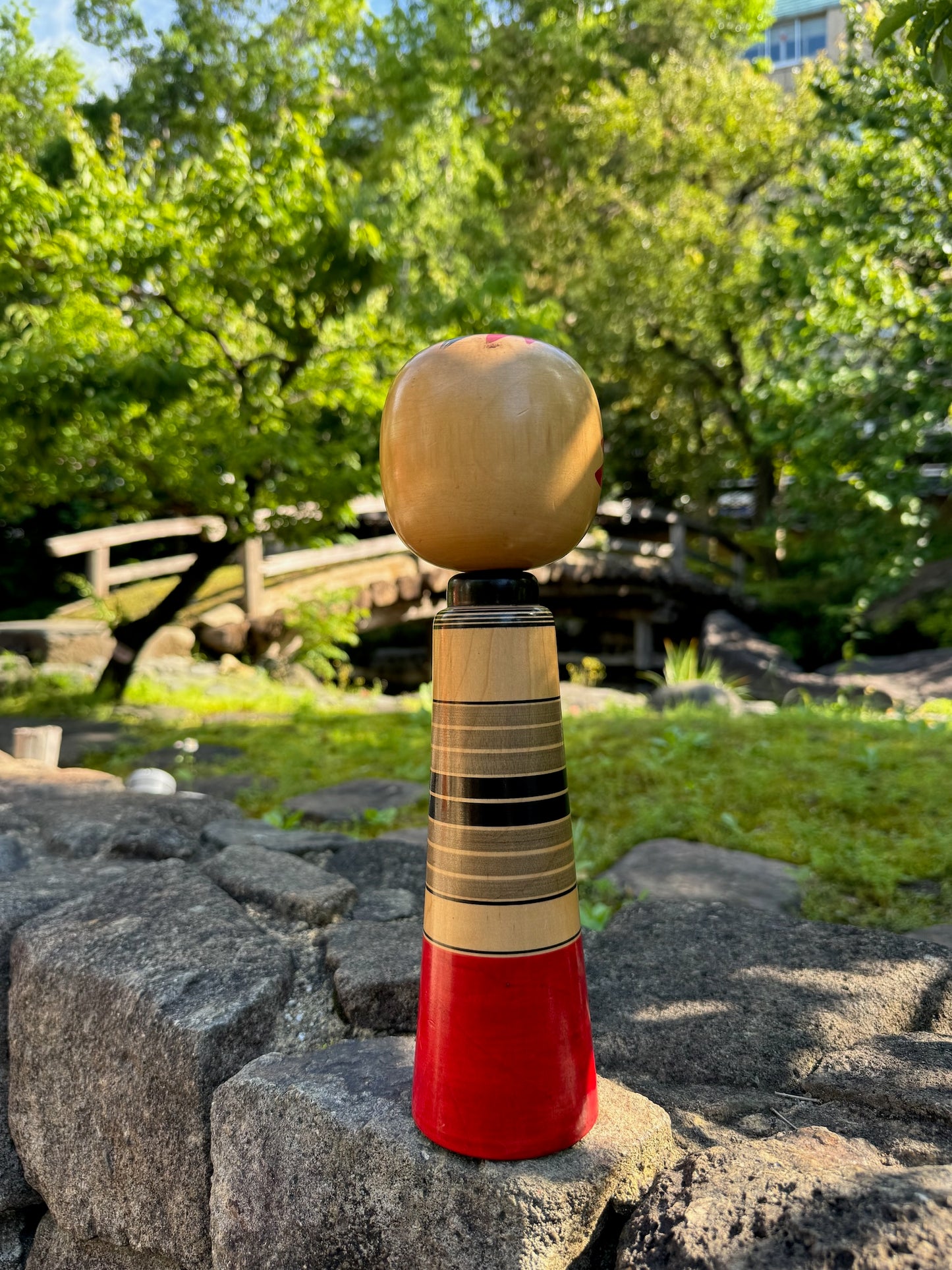 kokeshi poupée japoanise en bois avec tête de Daruma yeux en pièces de monnaies yen, vu de dos