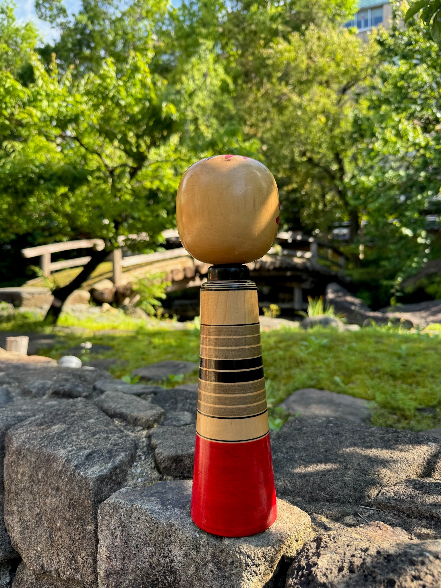 kokeshi poupée japoanise en bois avec tête de Daruma yeux en pièces de monnaies yen, vu de dos