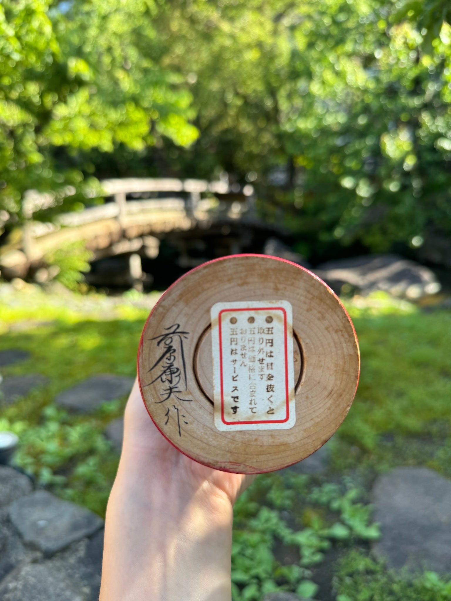 kokeshi poupée japoanise en bois avec tête de Daruma yeux en pièces de monnaies yen, signature de l'artisan