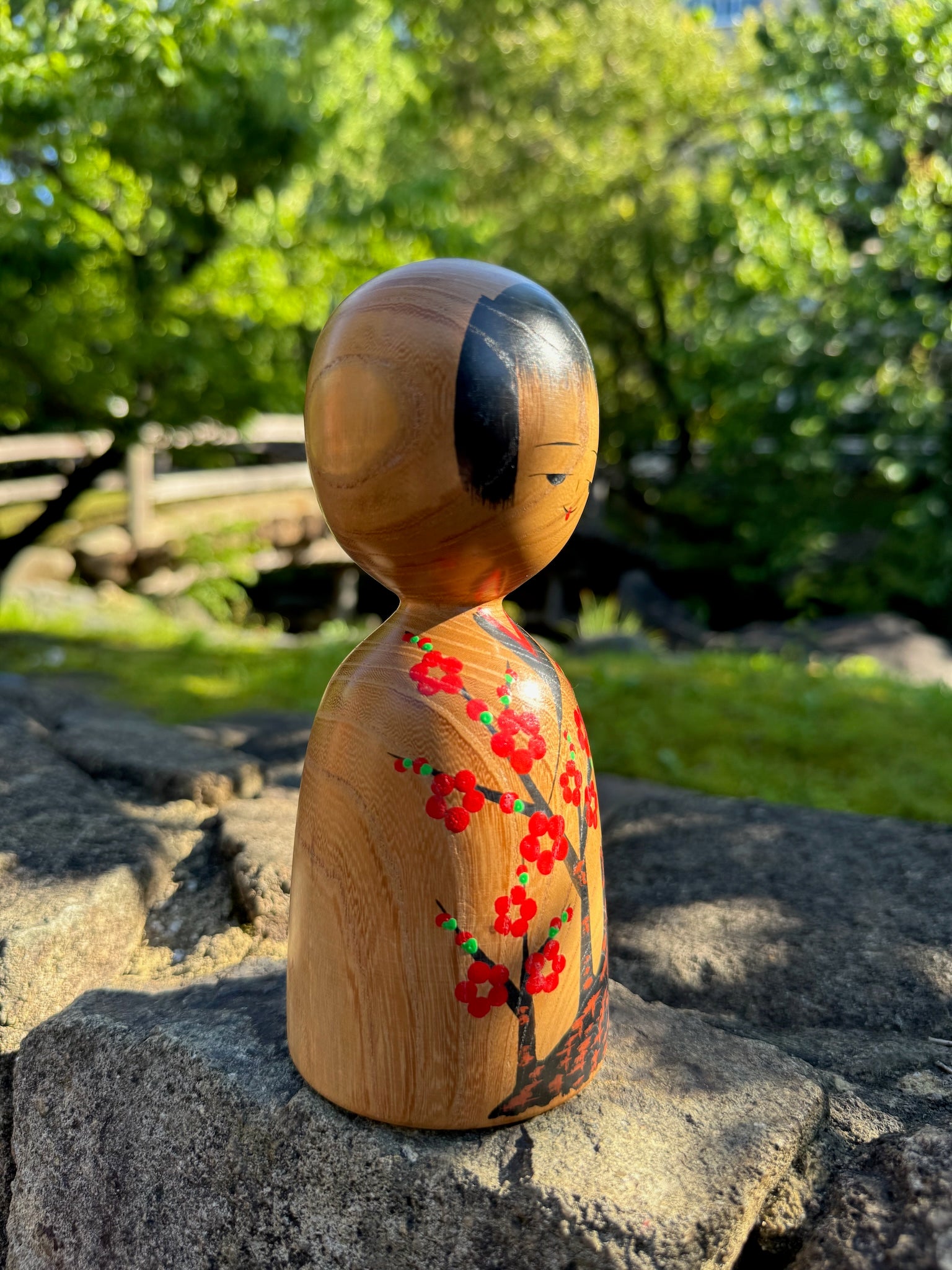 kokeshi, poupée japonaise traditionnelle en bois avec un motif de cerisier en fleurs, vu de profil