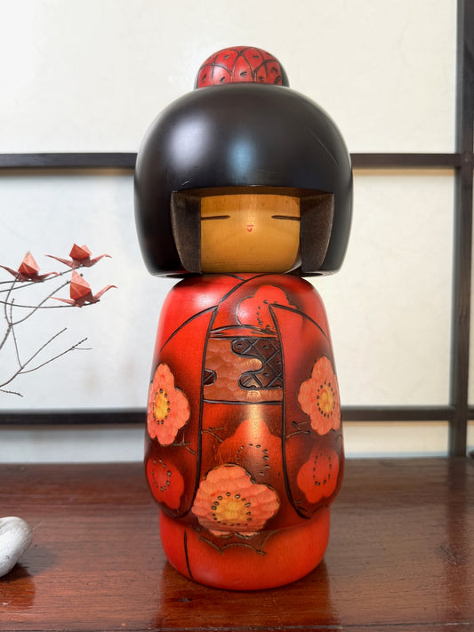 kokeshi poupée japonaise en bois de Masae Fujikawa, kimono rouge motif fleurs de cerisier roses et rouge, coiffure noire au carré avec chignon rouge