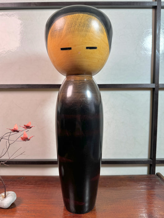 kokeshi de Watanabe Masao, nommé Shigo Sakura, corps laqué reflet rouge évoquant les cerisiers, tête cheveux noir, traits noirs pour les yeux