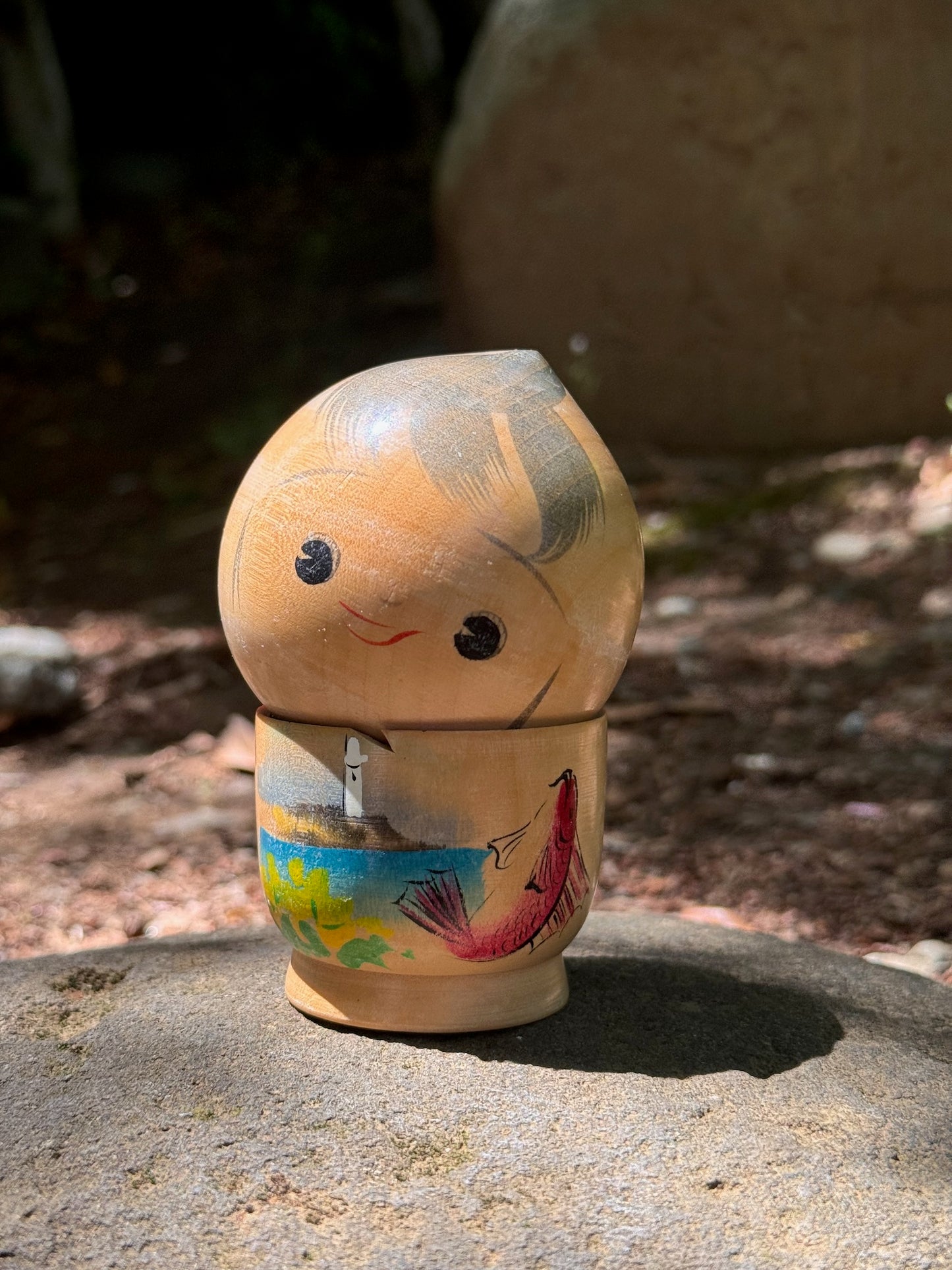 kokeshi poupée japonaise en bois souriante avec paysage bord de mer et poisson