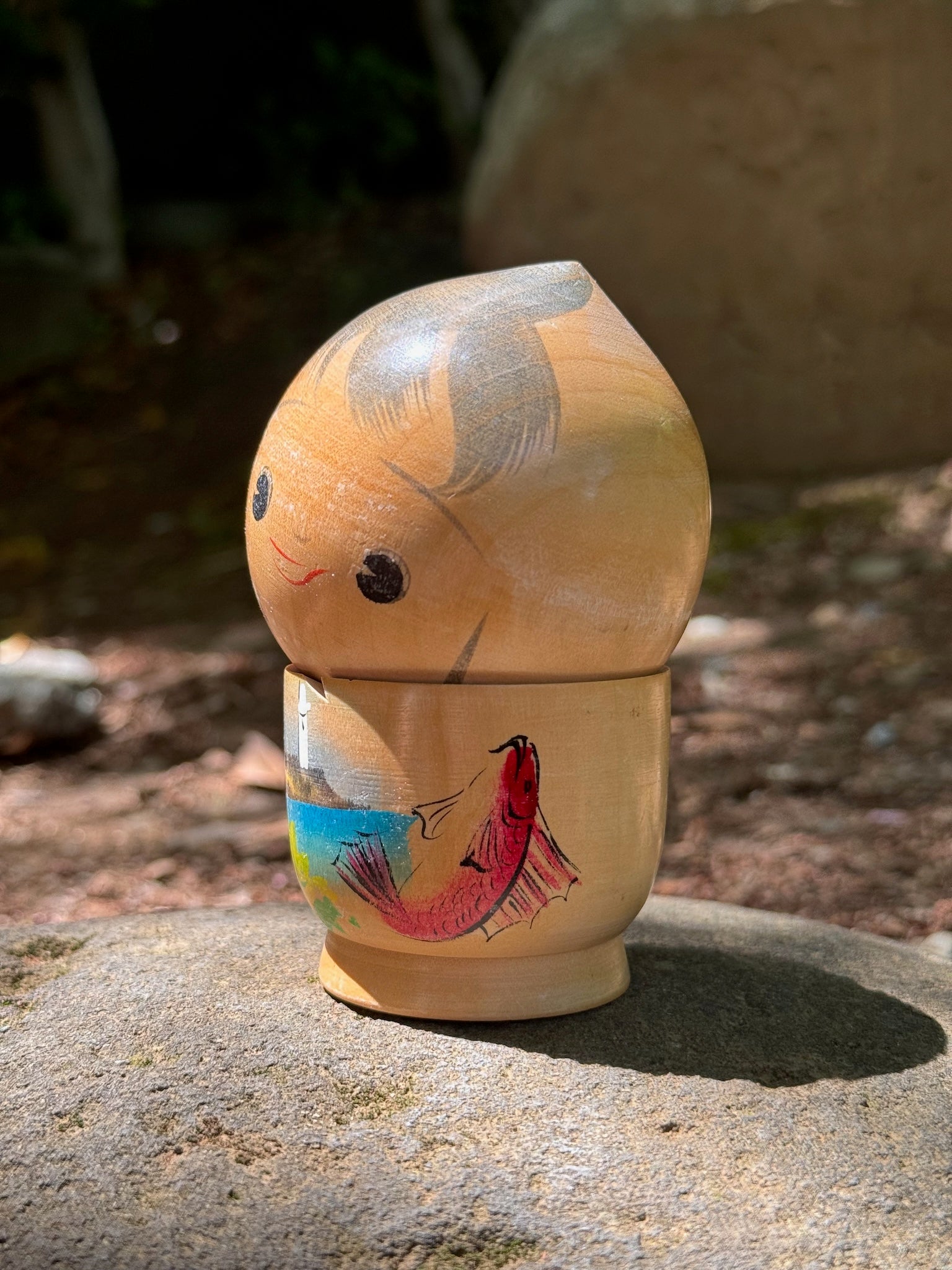 kokeshi poupée japonaise en bois souriante avec paysage bord de mer et poisson, profil gauche