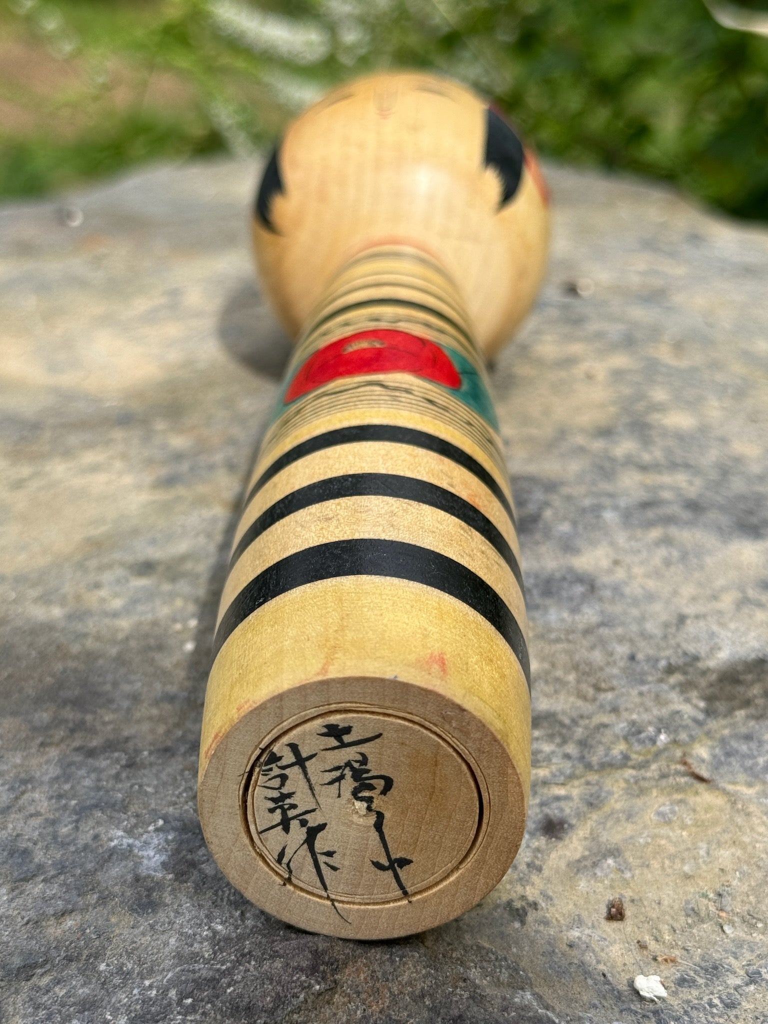 kokeshi, poupée japonaise traditionnelle en bois de Abe Kazue, à rayures et motif pivoine rouge, vu de dessous signture de l'artisan