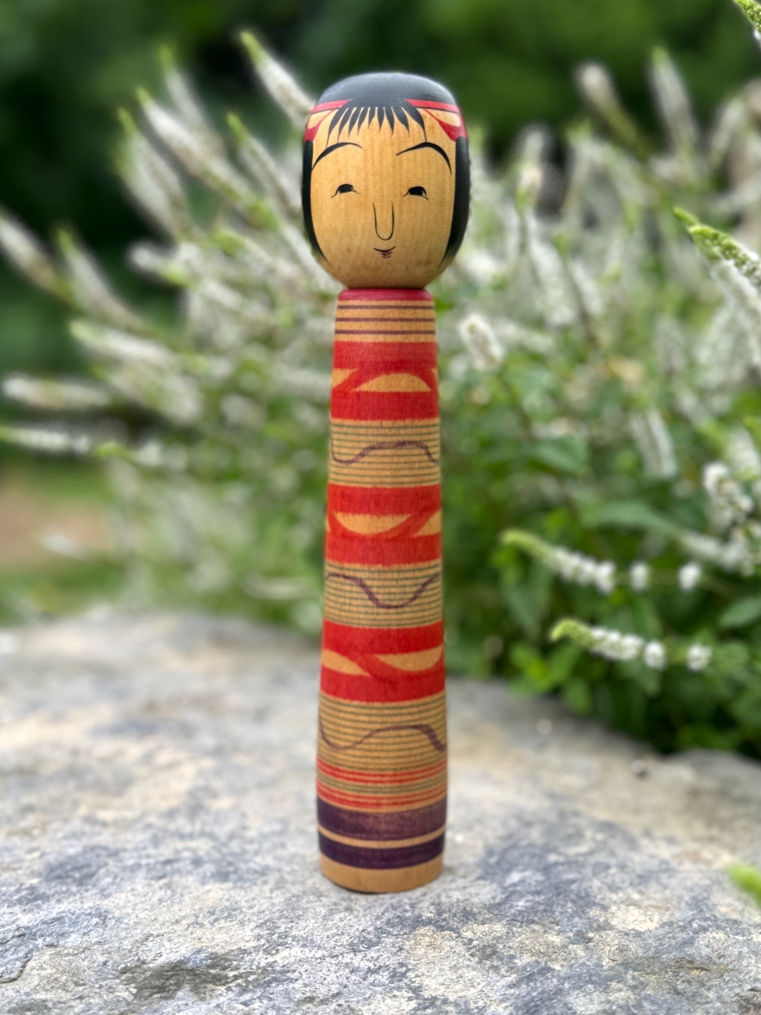 Kokeshi traditionnelle, poupée en bois japonaise de l'artisan Saito Hiromichi,  style Tsuchiyu. Visage souriant, corps long avec vague rouges rokuro et ondulations violettes. 