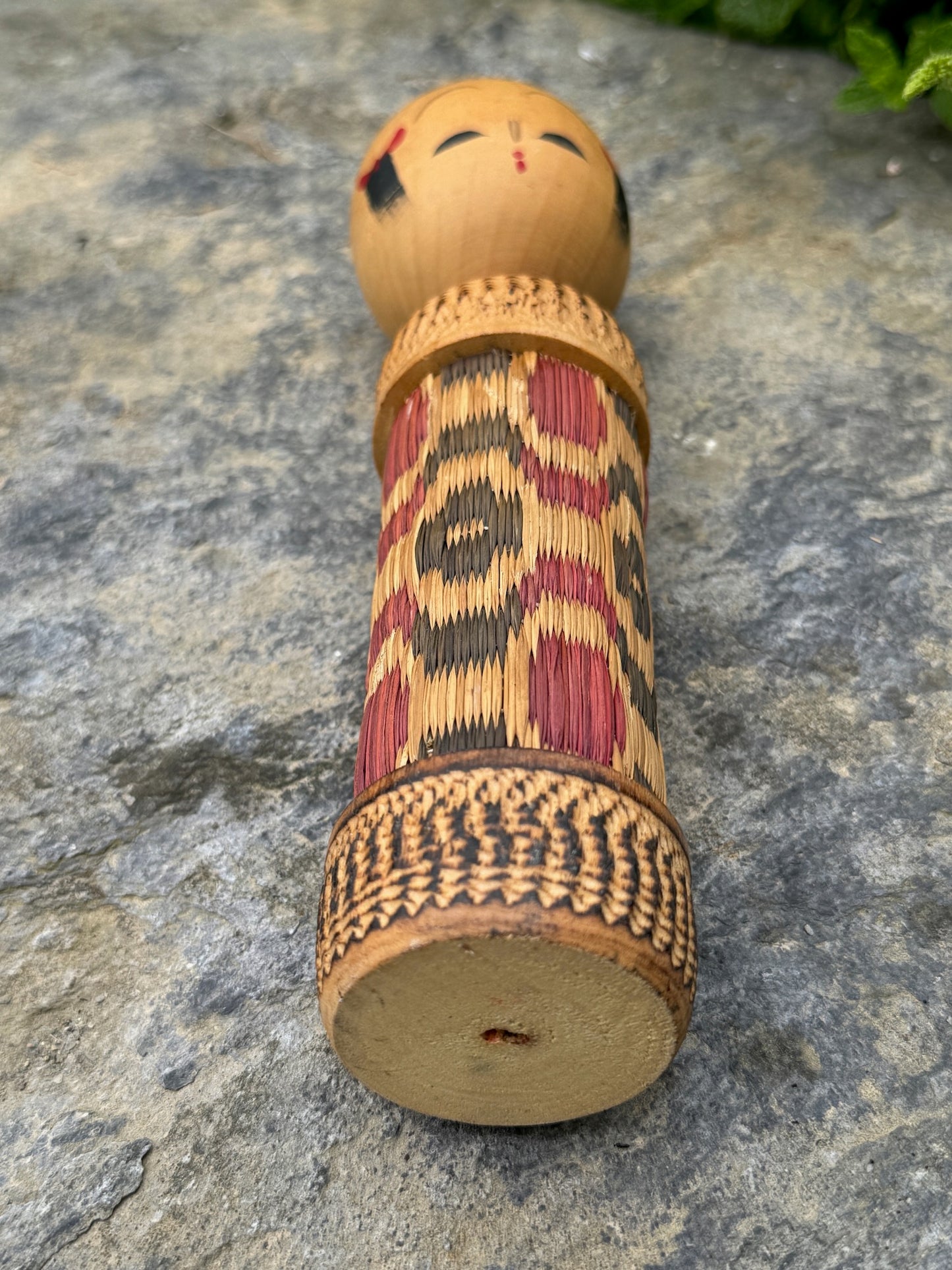 kokeshi, poupée japonaise en bois au corps en tatami à motif géométrique rouge et noir, couchée