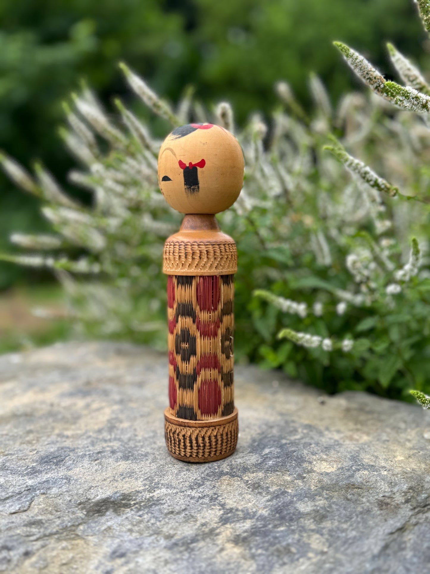 kokeshi, poupée japonaise en bois au corps en tatami à motif géométrique rouge et noir, profil gauche