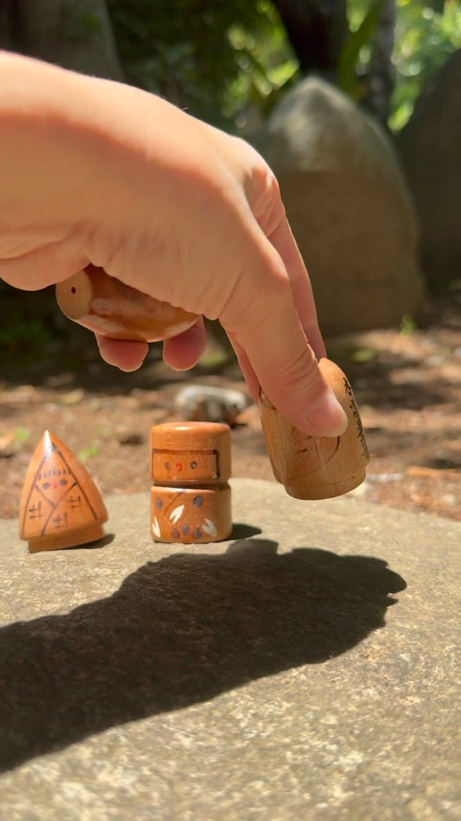 quatre kokeshi poupée japonaise en bois représentant les quatre saisons, prise dans une main