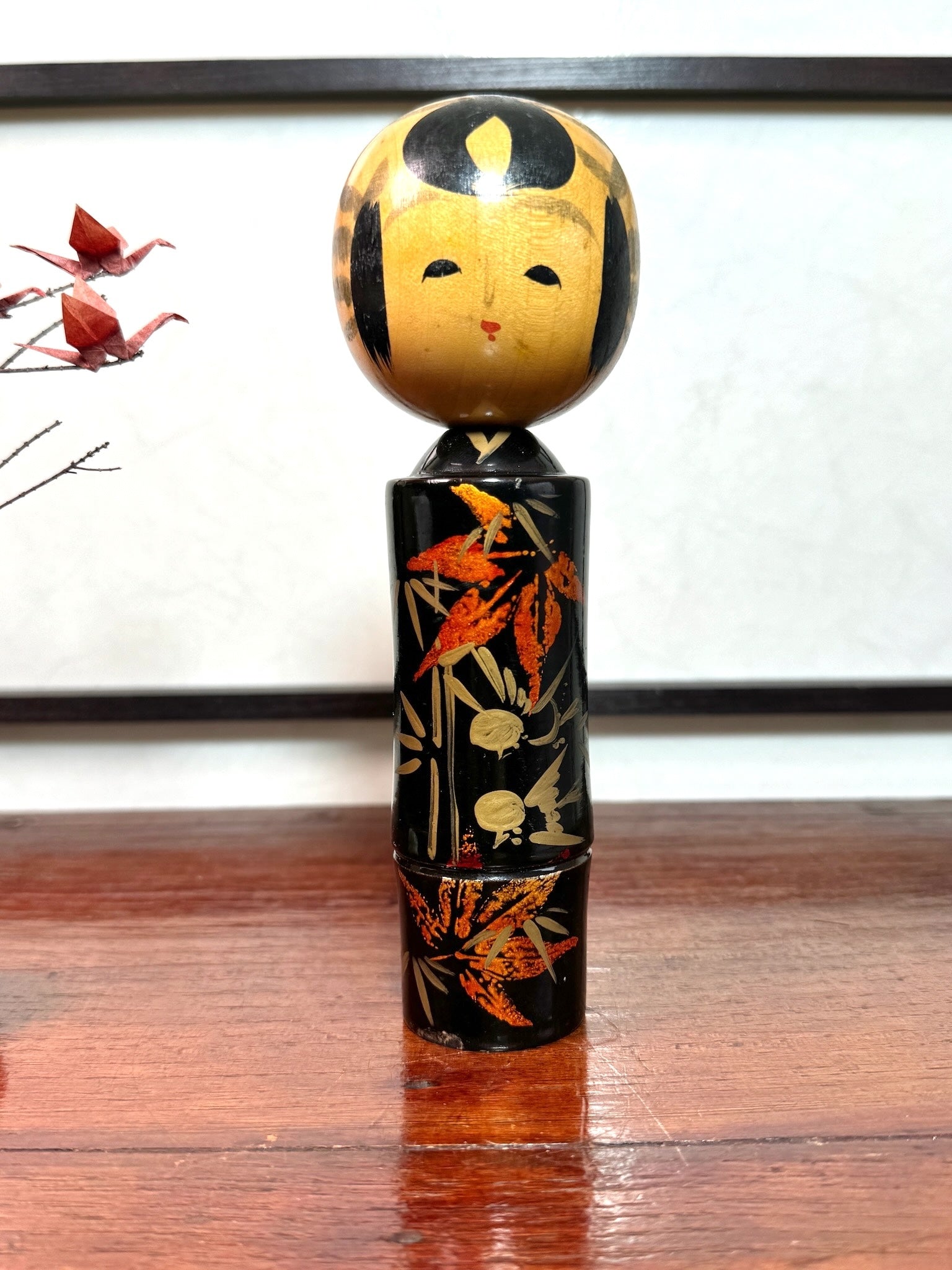 kokeshi, poupée japonaise en bois laqué noir de Takahashi Tatsuro, motif feuilles d'érable orange et bambou