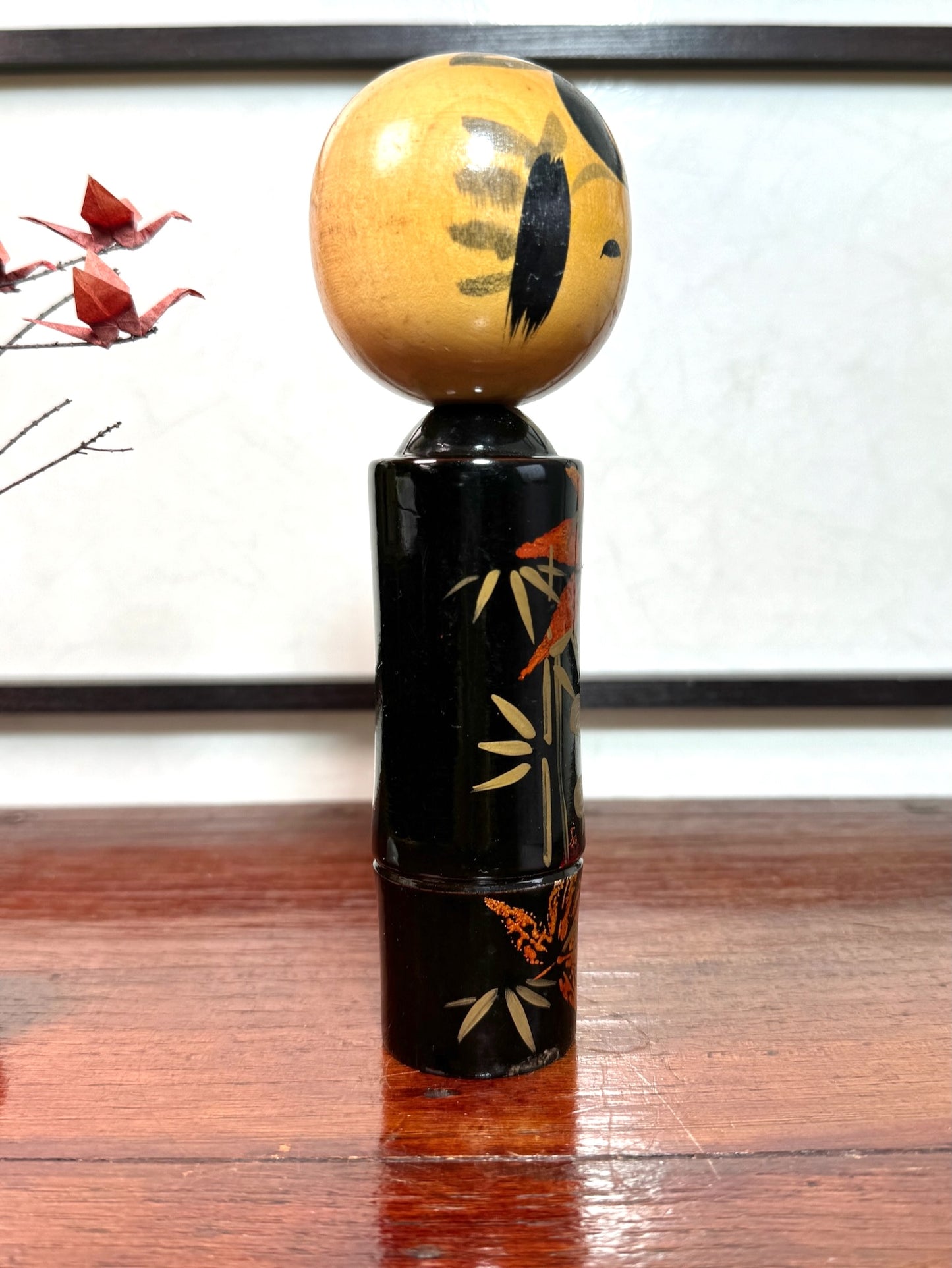 kokeshi, poupée japonaise en bois laqué noir de Takahashi Tatsuro, motif feuilles d'érable orange et bambou, profil droit