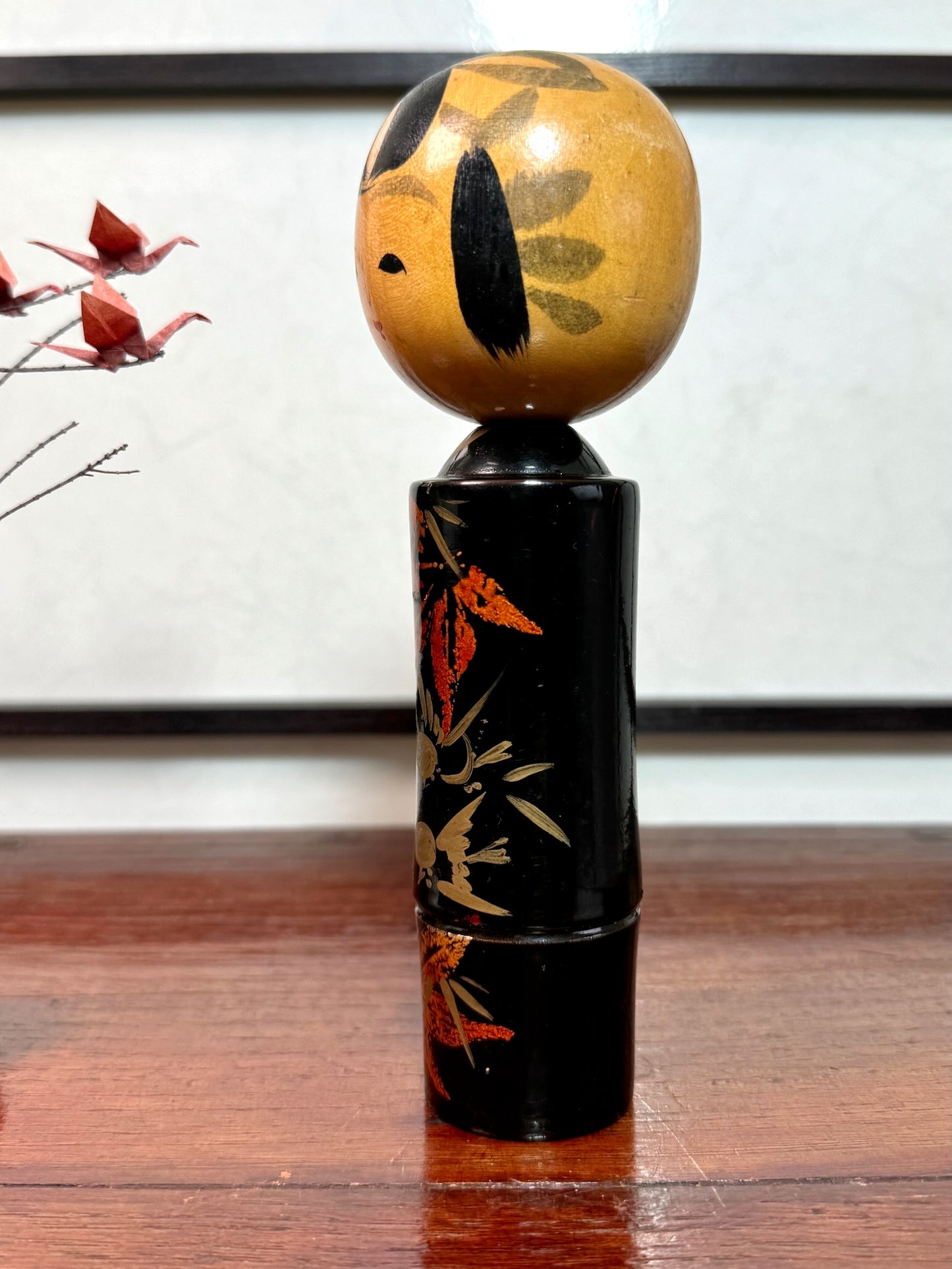 kokeshi, poupée japonaise en bois laqué noir de Takahashi Tatsuro, motif feuilles d'érable orange et bambou, profil gauche