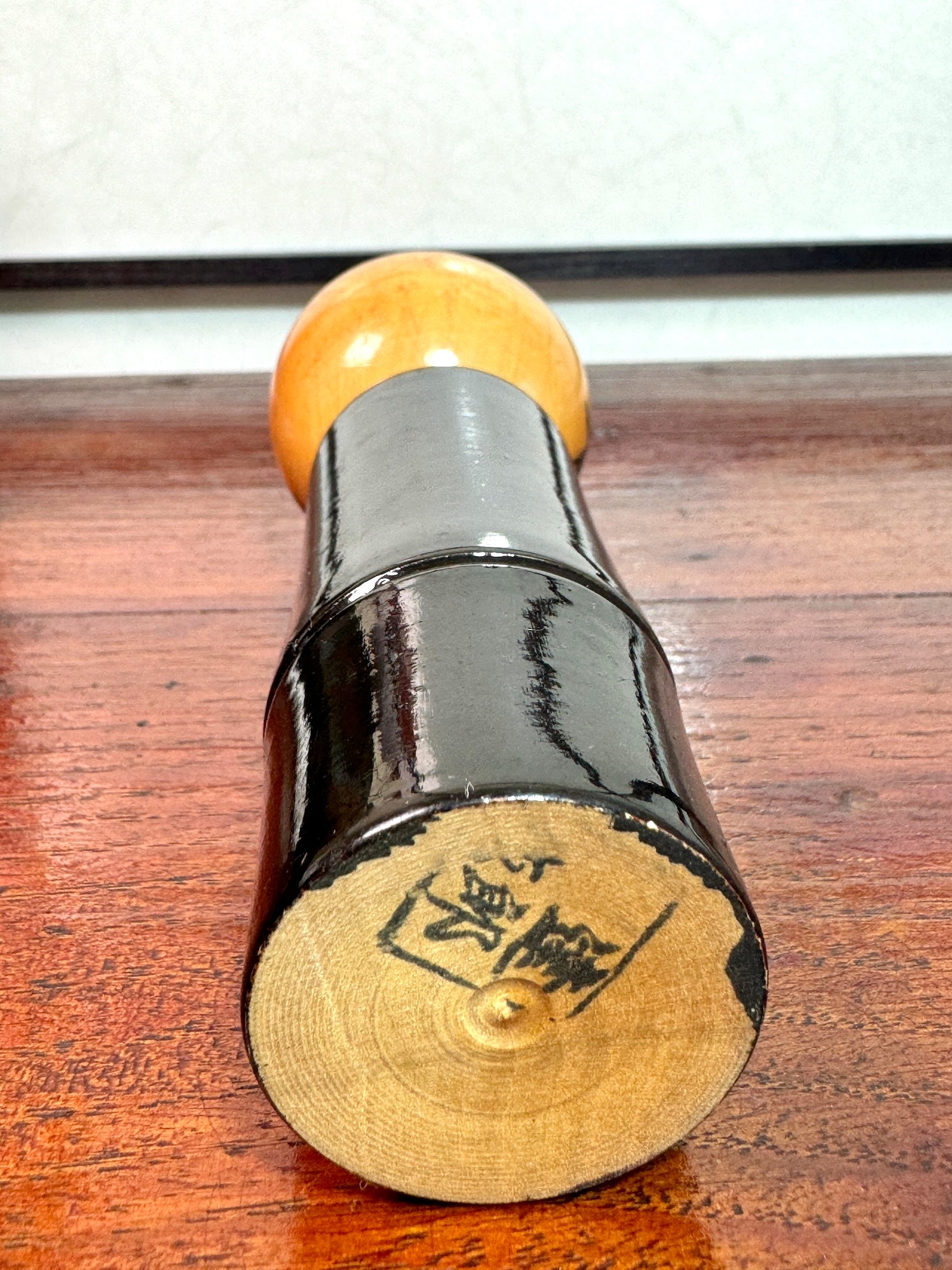 kokeshi, poupée japonaise en bois laqué noir de Takahashi Tatsuro, motif feuilles d'érable orange et bambou, le sceau de l'artisan au dessous