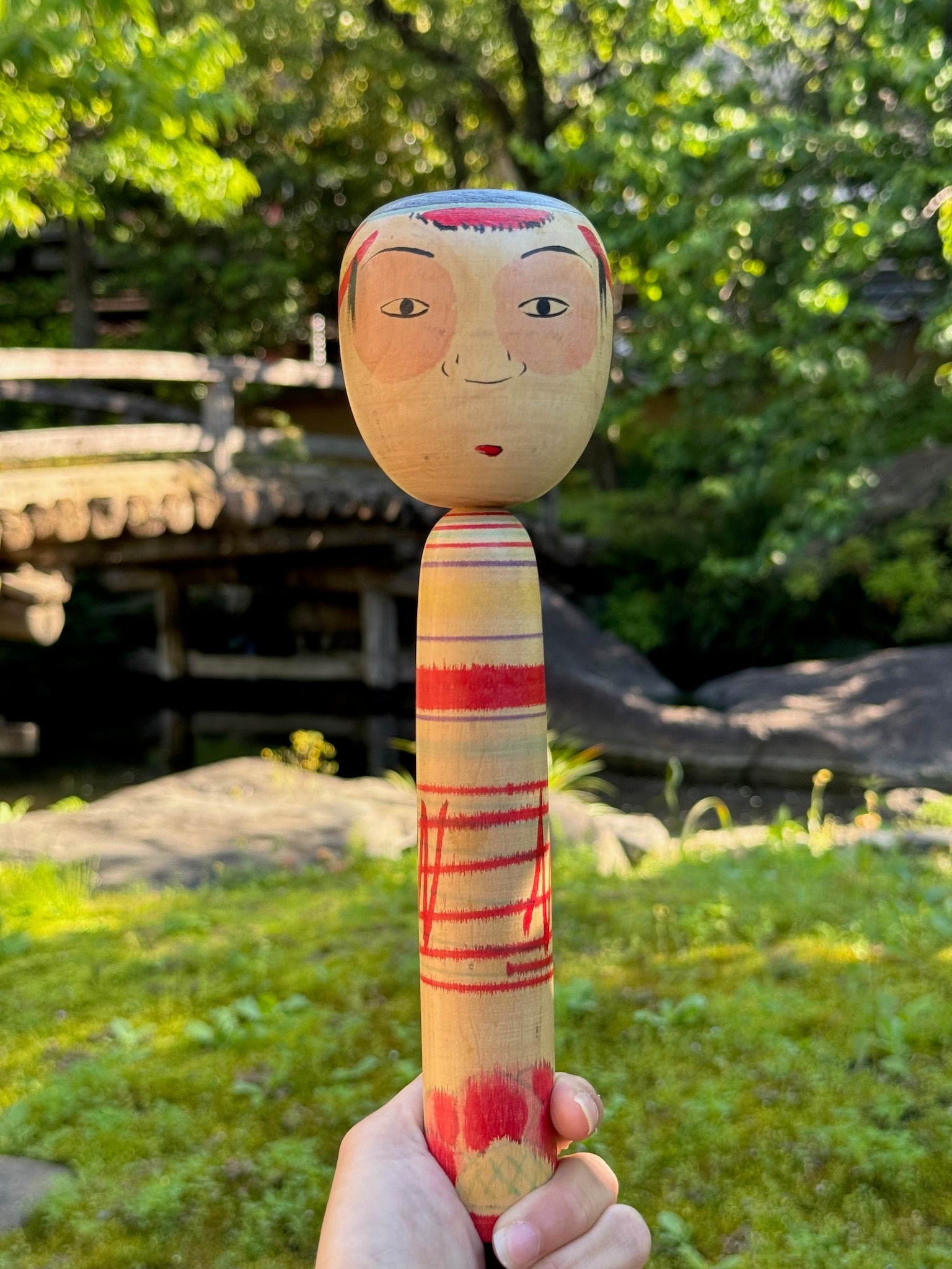 kokeshi poupée japonaise aux grands yeux cernés de rose et à l'expression étonnée