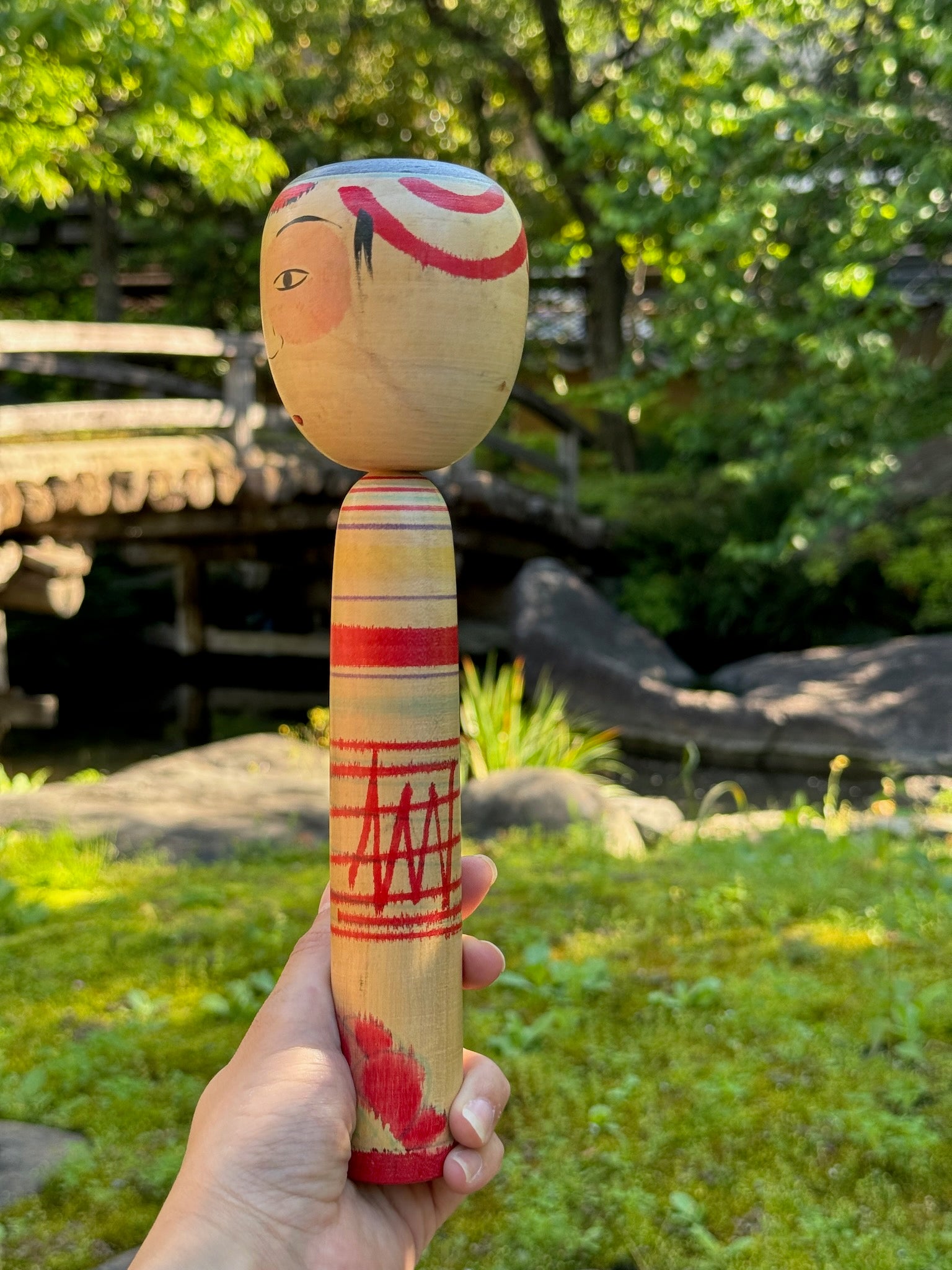 kokeshi poupée japonaise aux grands yeux cernés de rose et à l'expression étonnée, profil gauche