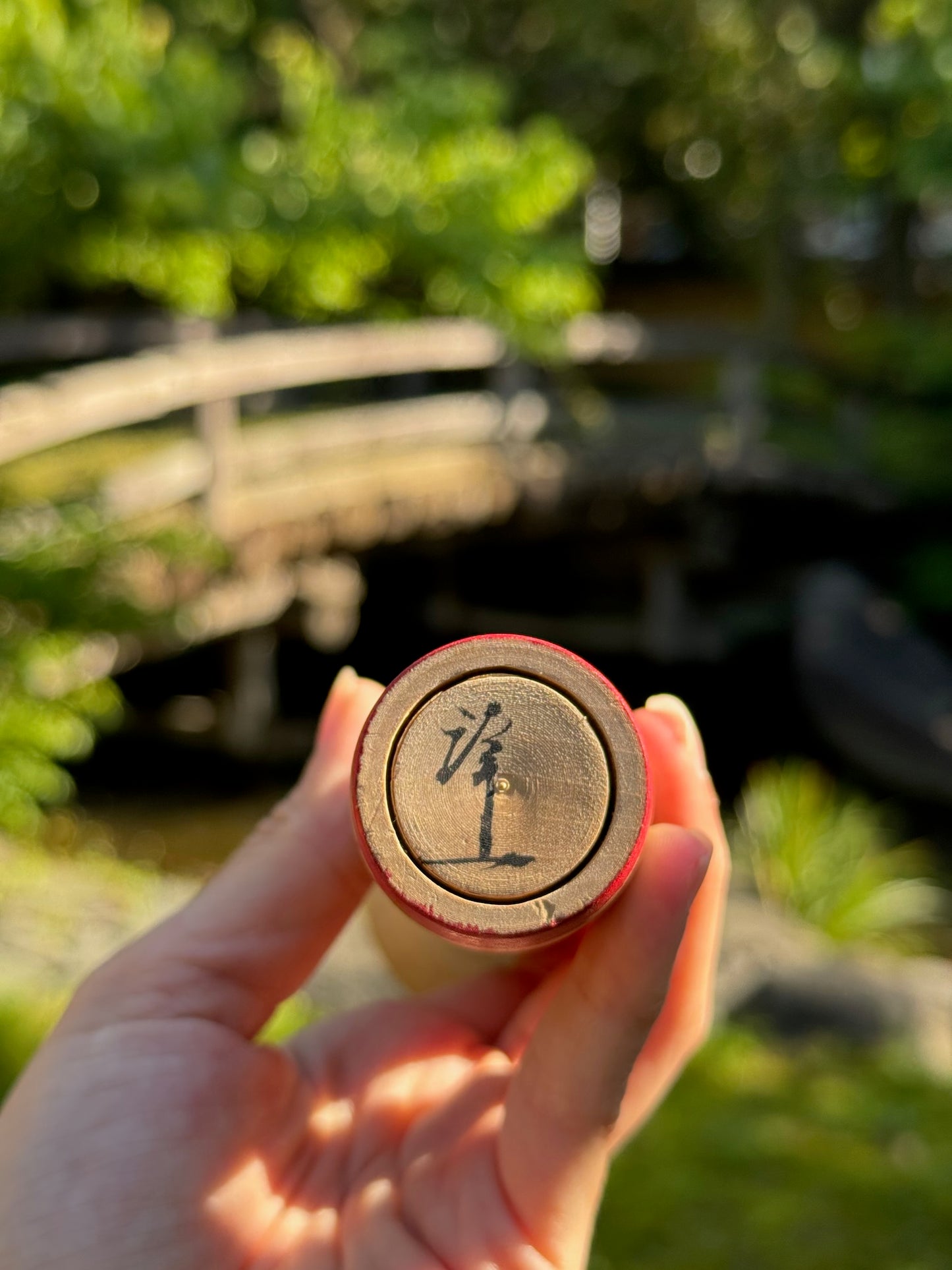 kokeshi poupée japonaise aux grands yeux cernés de rose et à l'expression étonnée, signature de l'artisan Arakawa Yoichi