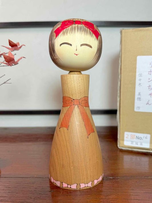 Kokeshi créative sosaku, ribon chan de Miho Sasaki. Poupée japonaise en bois, pyrogravée de rubans roses, visage souriant. 