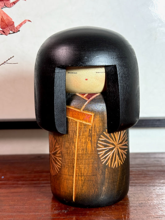 kokeshi de Sekiguchi Sansaku, coiffure en carré noir, visage en bois clair, corps gravé de chrysanthèmes stylisés