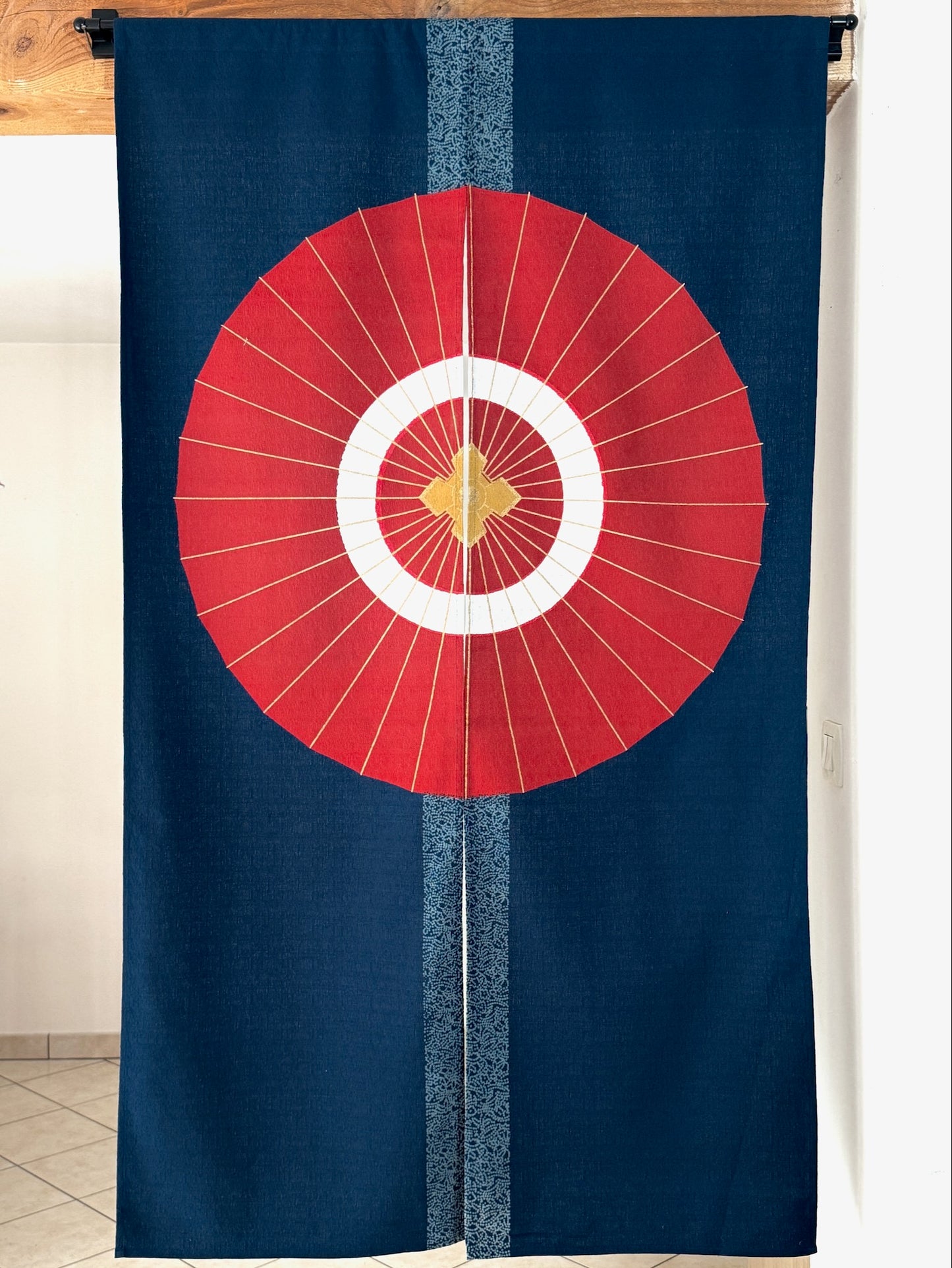 Noren japonais bleu foncé avec un motif d'ombrelle rouge et cercles blancs, symbole de protection et d'élégance japonaise, utilisé dans les cérémonies traditionnelles.

