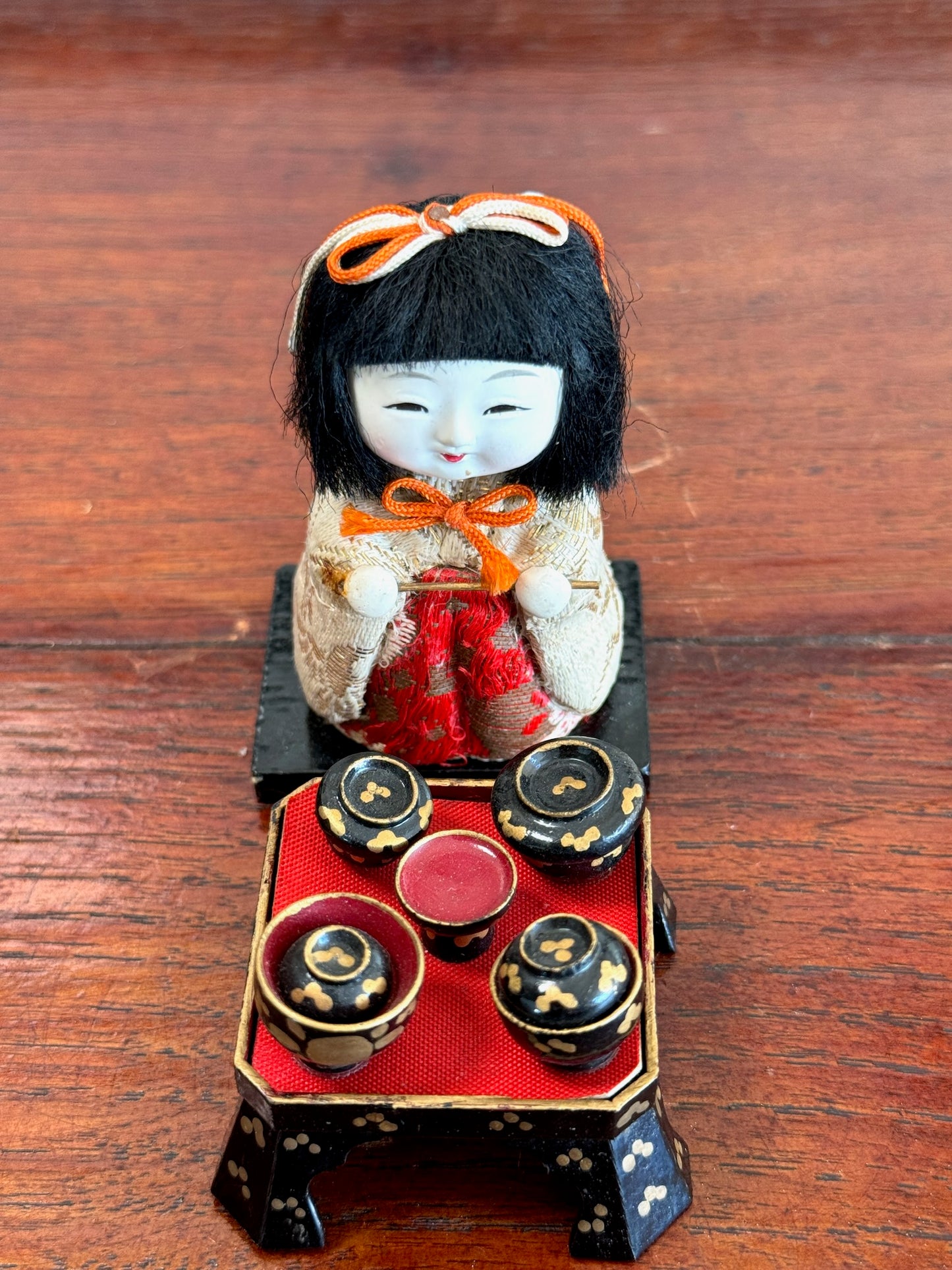poupée japonaise kimekomi miniature avec plateau repas en laque noire, vu de dessus