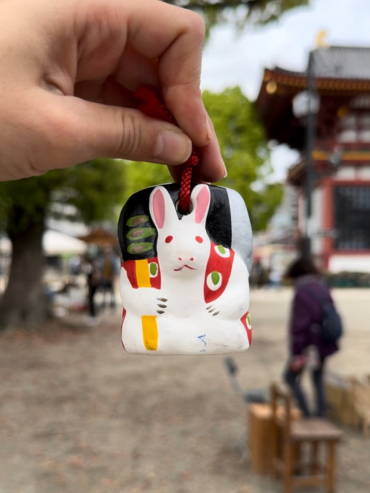 Clochette japonaise en céramique en forme de lapin suspendue par une ficelle rouge 