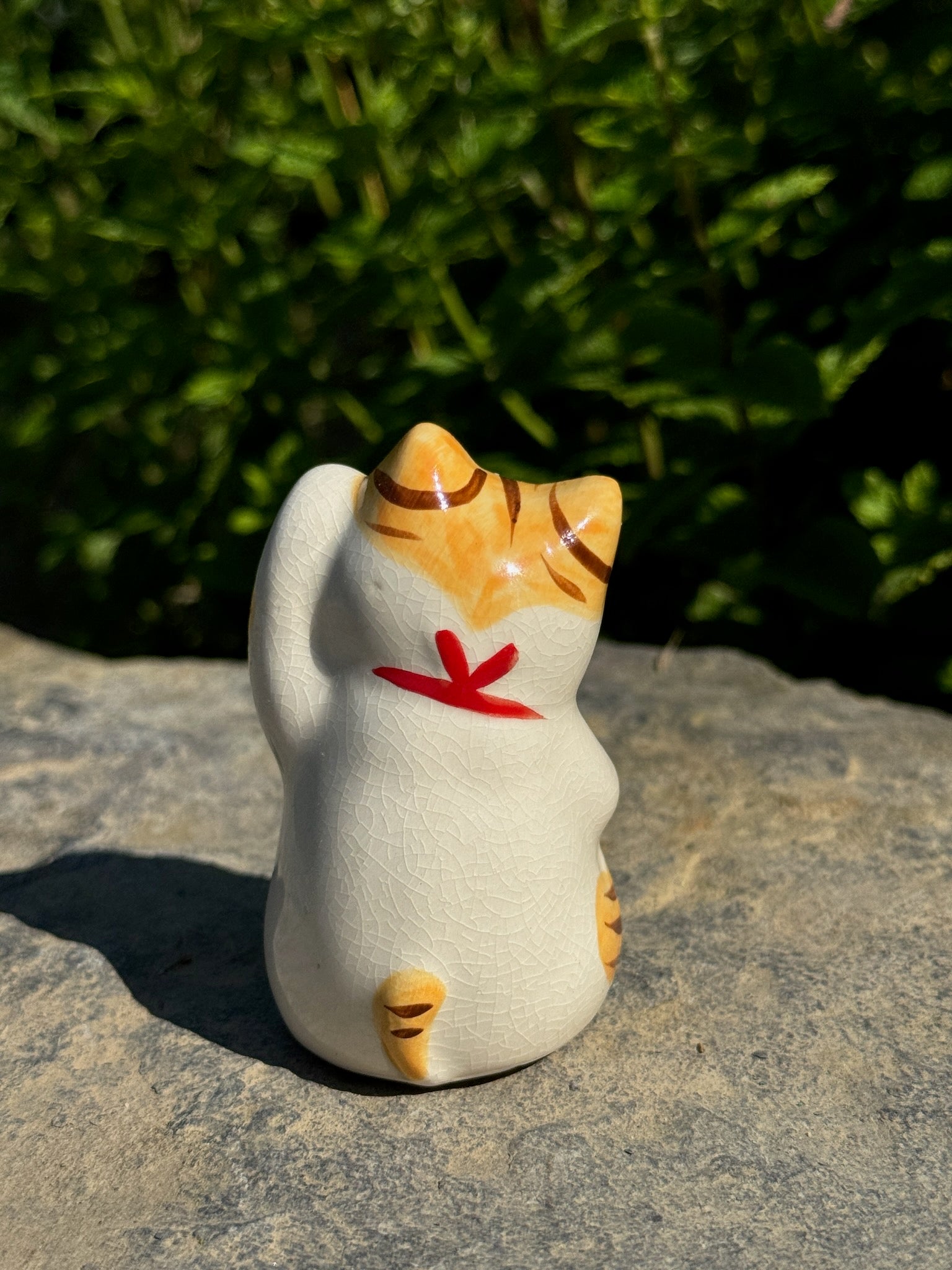 chat japonais Maneki Neko en céramique blanc et jaune, vu de dos, queue jaune et noeud rouge