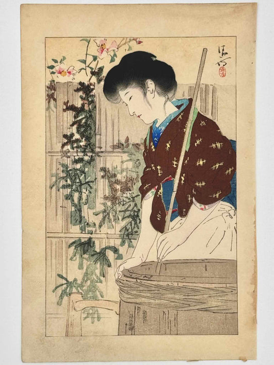 Estampe Japonaise de Kiyokata Kaburagi, femme préparant du saké. Elle tient une tige de bambou qu'elle tourne dans un baril en bois. Manches de kimono marron retroussées, tablier blanc. Arrière plan palissade en bois avec plante grimpante, clématite fleurs roses. 