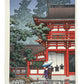 estampe japonaise de Hasui paysage de pluie, deux personnes sous un parapluie sur un temple rouge à Nara