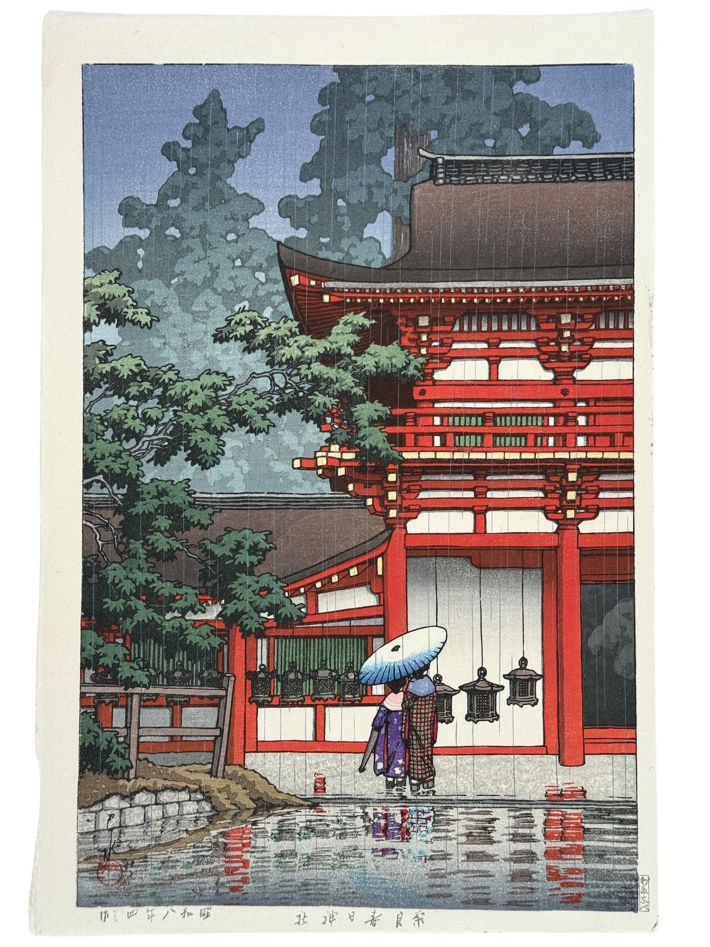 estampe japonaise de Hasui paysage de pluie, deux personnes sous un parapluie sur un temple rouge à Nara