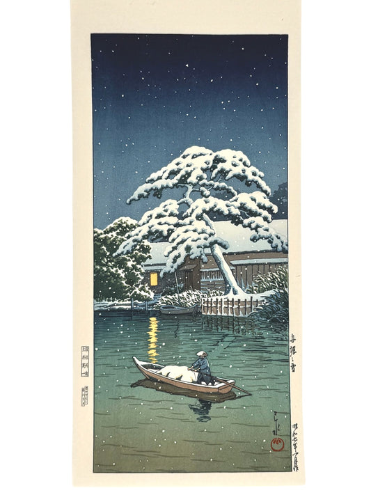 estampe japonaise de hasui kawase, paysage de nuit en hiver, un pêcheur dans une barque sur une rivière passe devant un arbre recouvert de neige