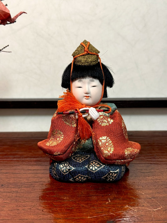 poupée japonaise gosho avec une flûte traversière dans les mains, en kimono orange. musicien pour le Hina Matsuri