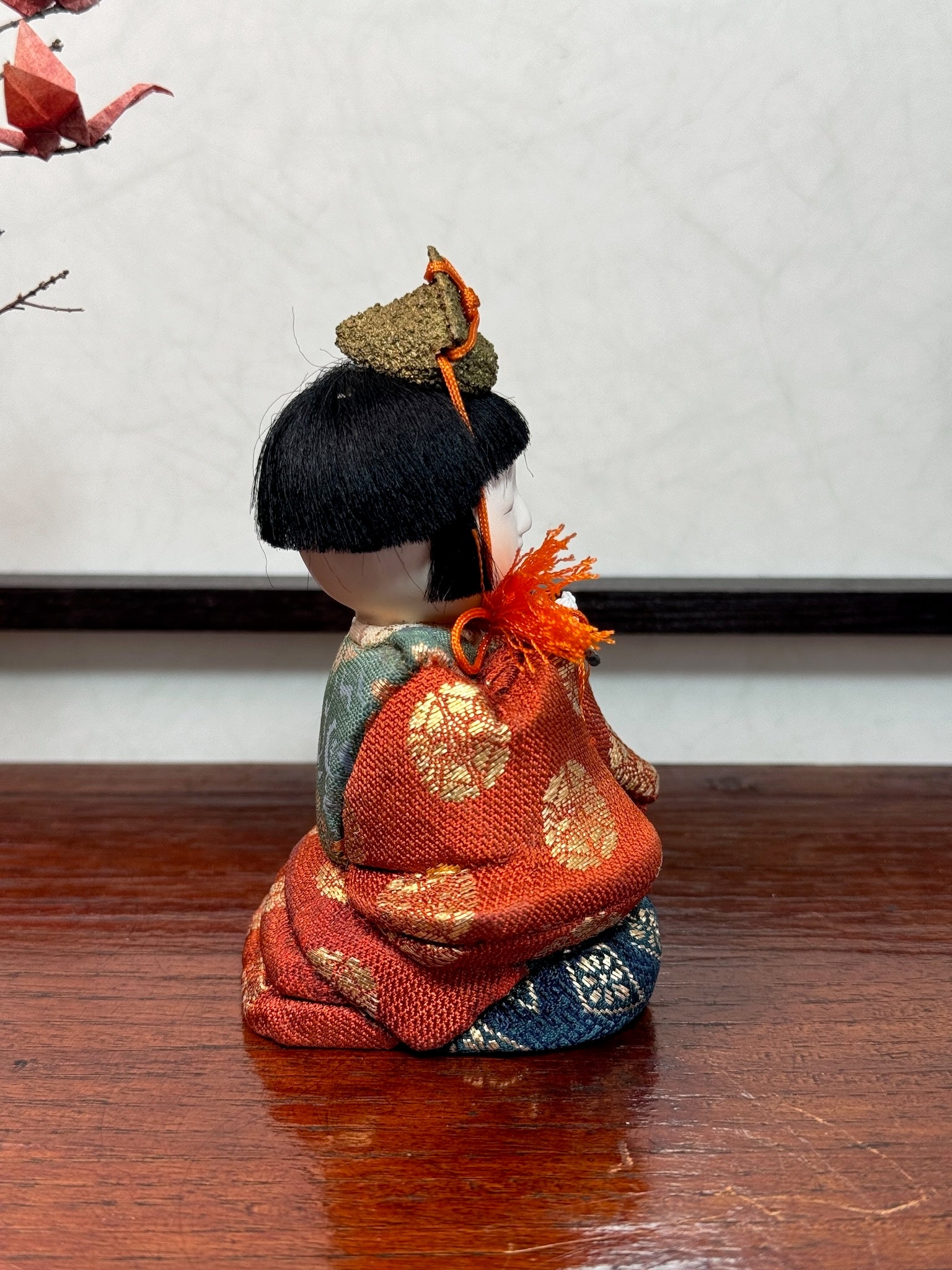 poupée japonaise gosho avec une flûte traversière dans les mains, en kimono orange. musicien pour le Hina Matsuri, profil droit