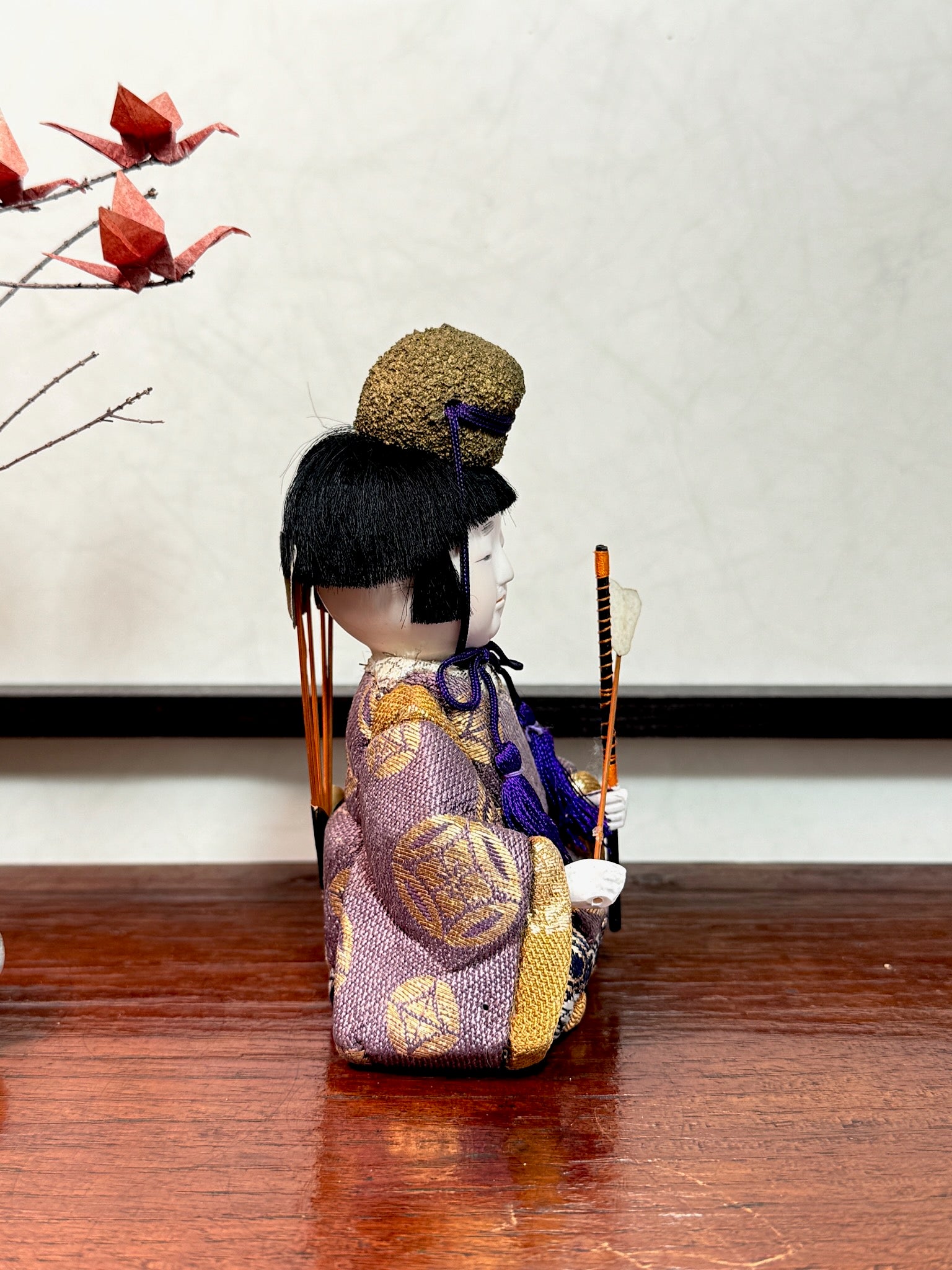 Poupée japonaise gosho kimekomi, un archer avec ses flèches dans le dos, une flèche dans une main vêtu d'un kimono violet et or, profil droit