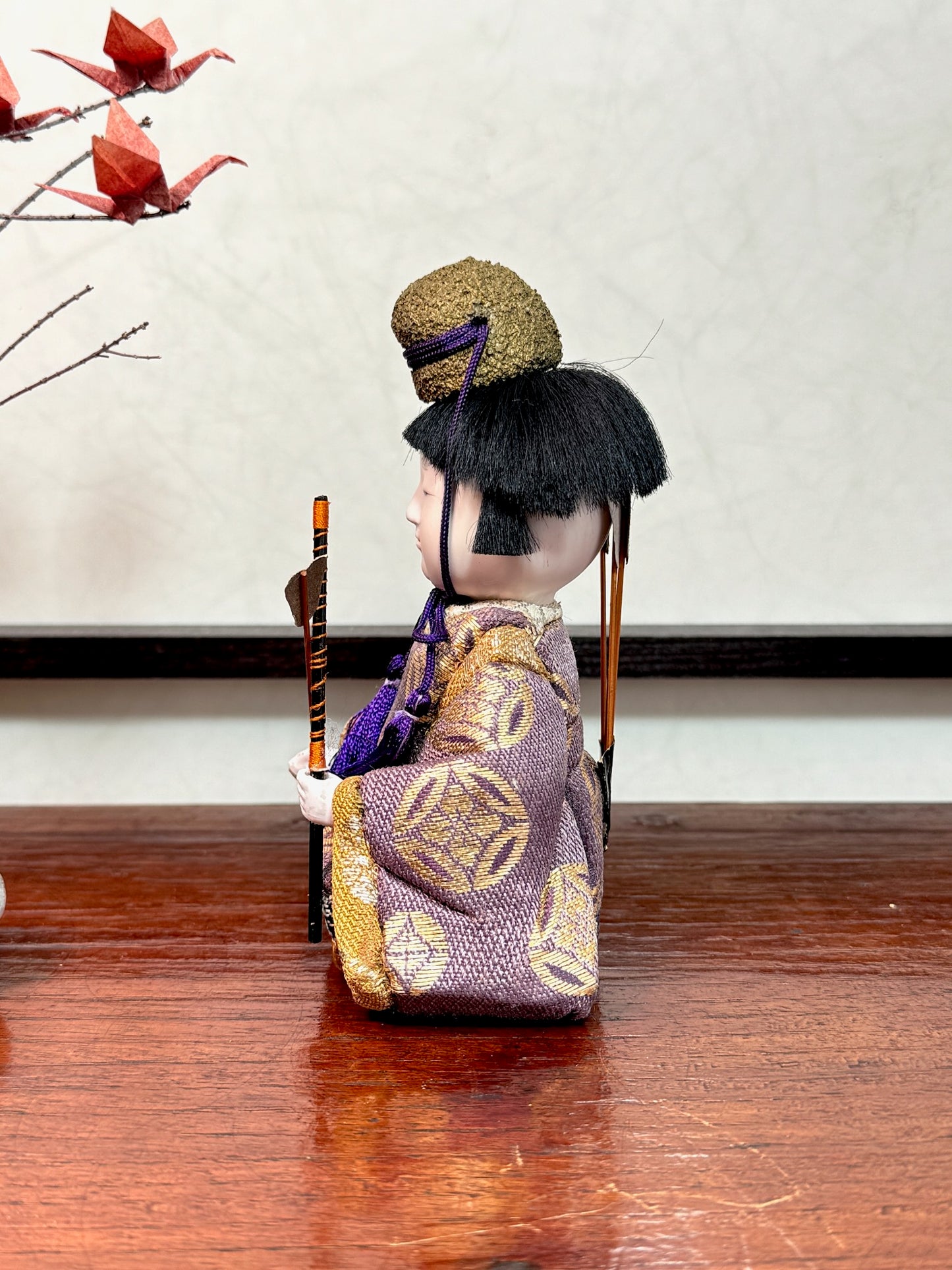 Poupée japonaise gosho kimekomi, un archer avec ses flèches dans le dos, une flèche dans une main vêtu d'un kimono violet et or, profil gauche