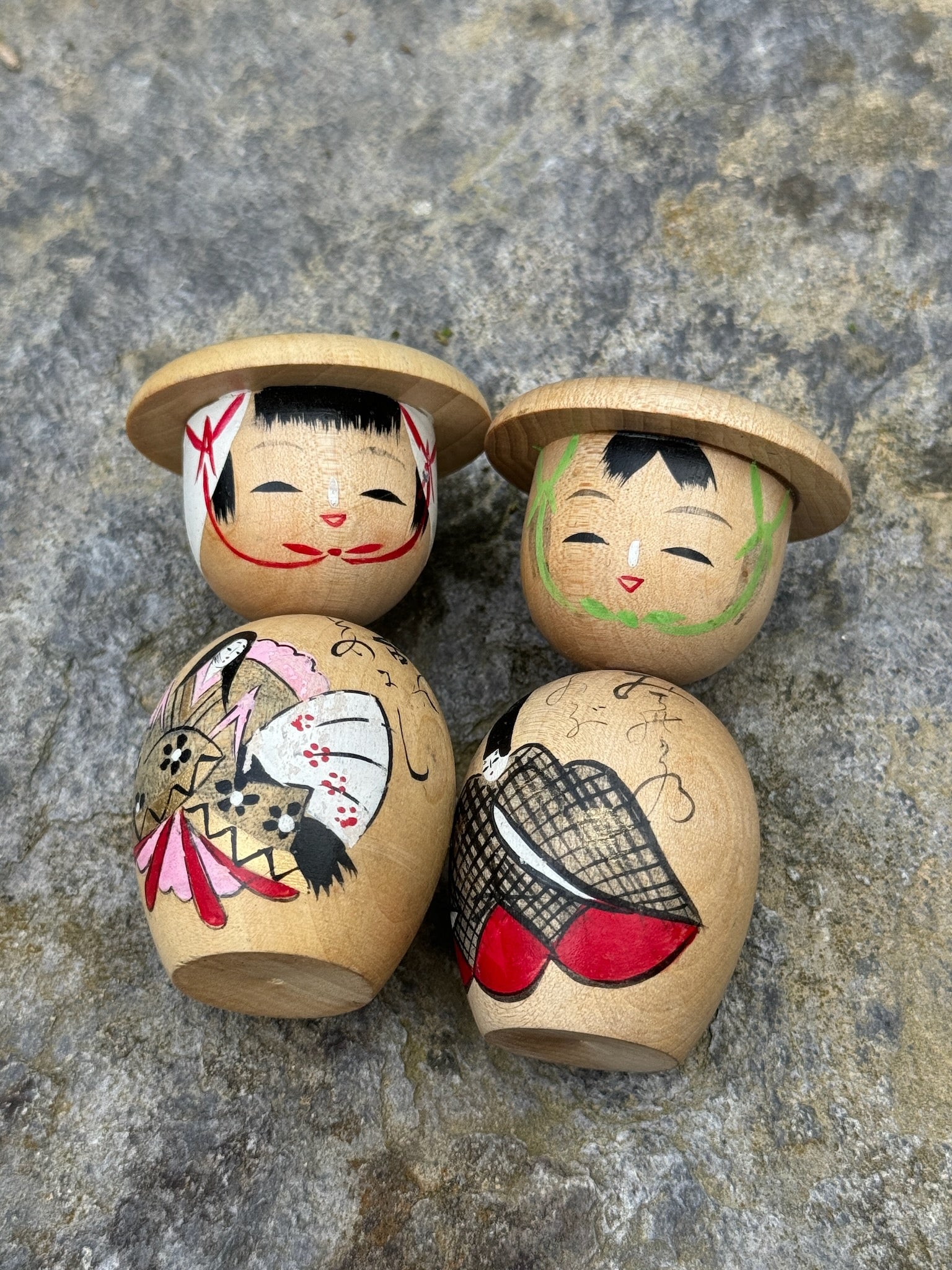 Couple de poupées kokeshi en bois représentant un empereur et une impératrice avec des chapeaux ronds, décorées de motifs traditionnels peints à la main vue dessus