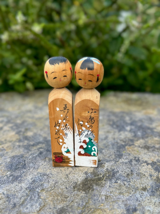 Couple de poupées kokeshi en bois avec motif de vague et inscriptions japonaises 
