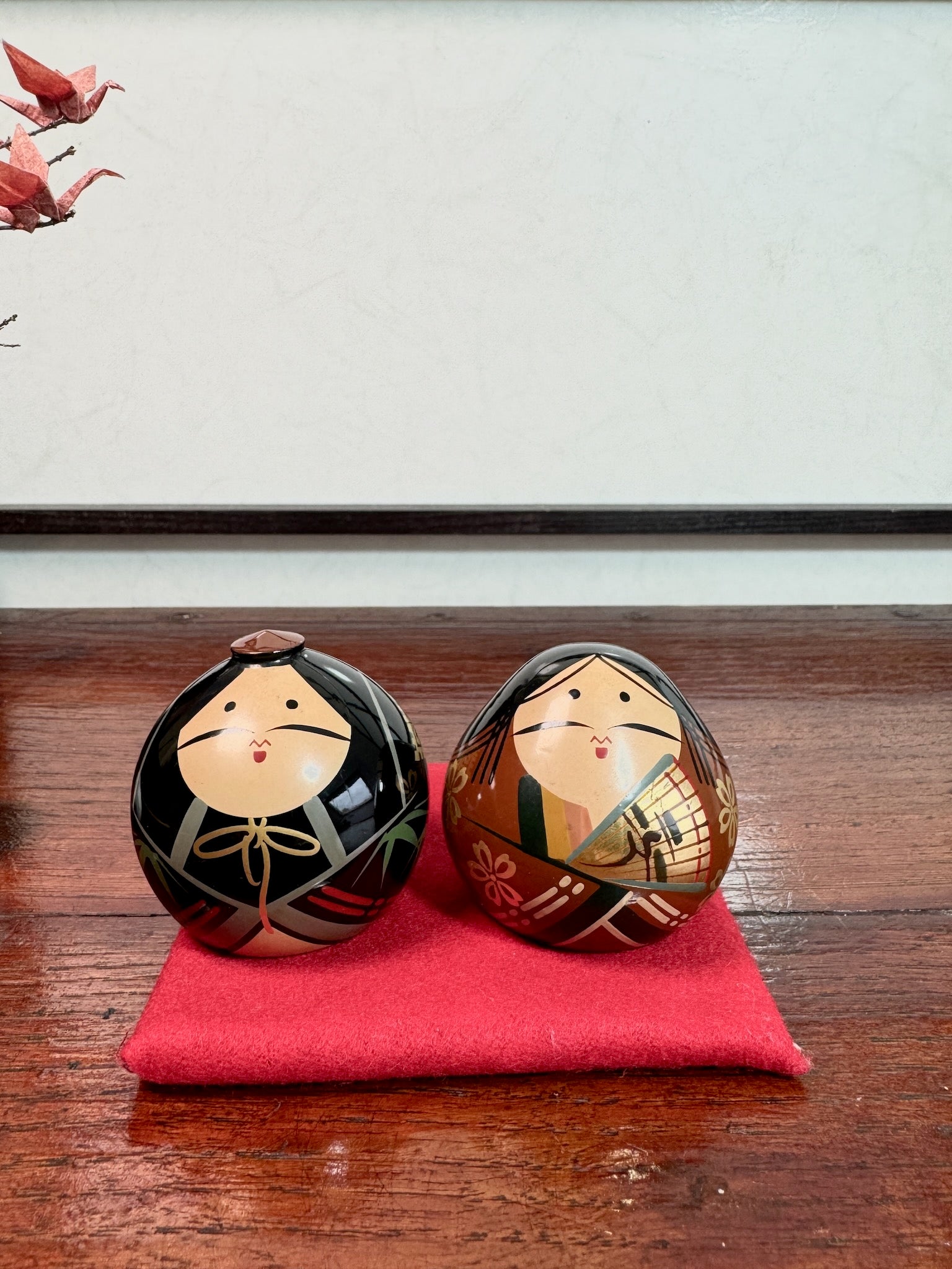 couple de kokeshi en laque représentant l'empereur et l'impératrice Meiji, sur tapis rouge