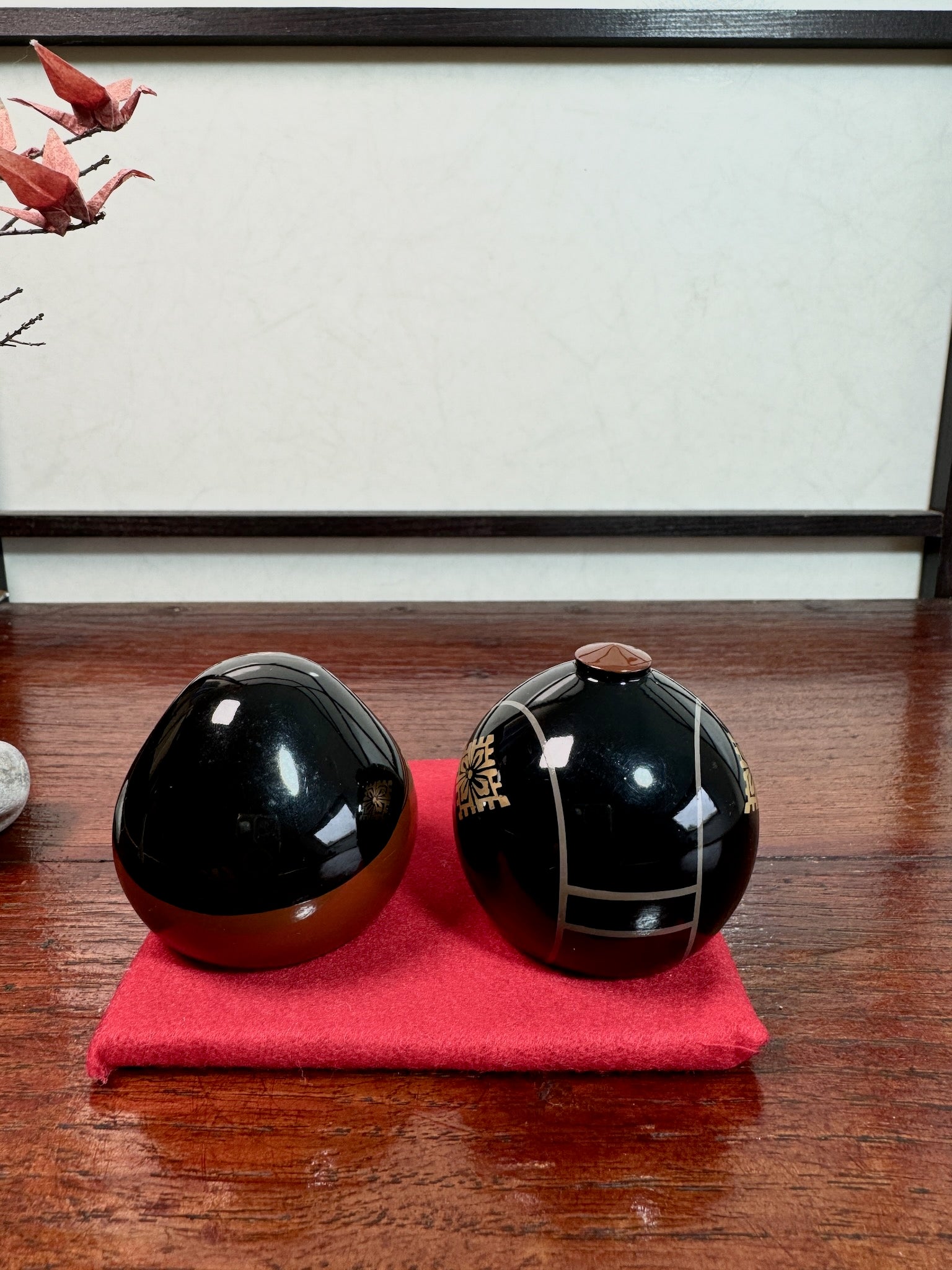 couple de kokeshi en laque représentant l'empereur et l'impératrice Meiji, sur tapis rouge, vu de dos