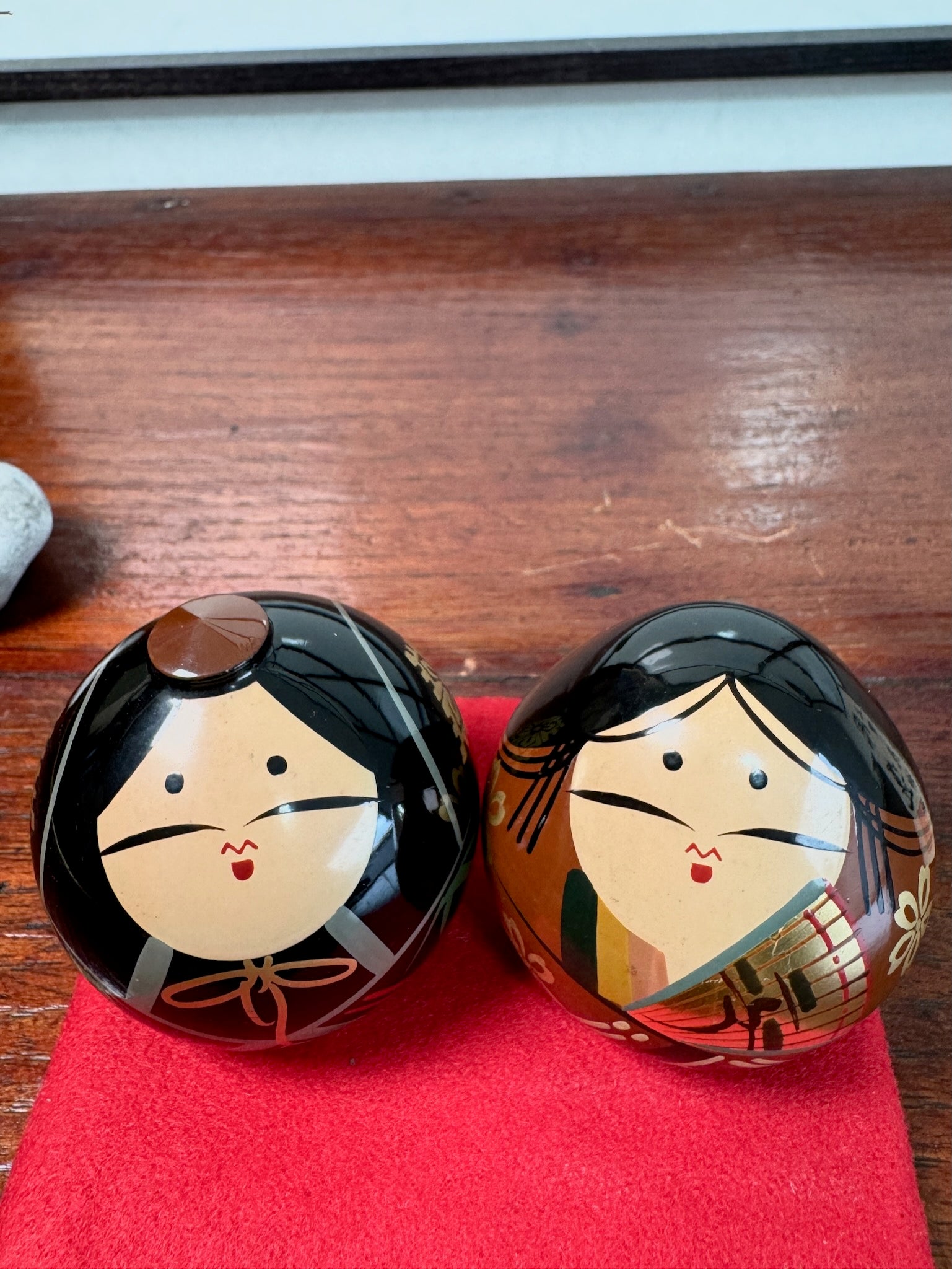 couple de kokeshi en laque représentant l'empereur et l'impératrice Meiji, sur tapis rouge, leur visage souriant