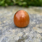 Poupée daruma en bois de forme ronde avec des détails peints noirs et rouges et un caractère japonais sur le devant vue de dos
