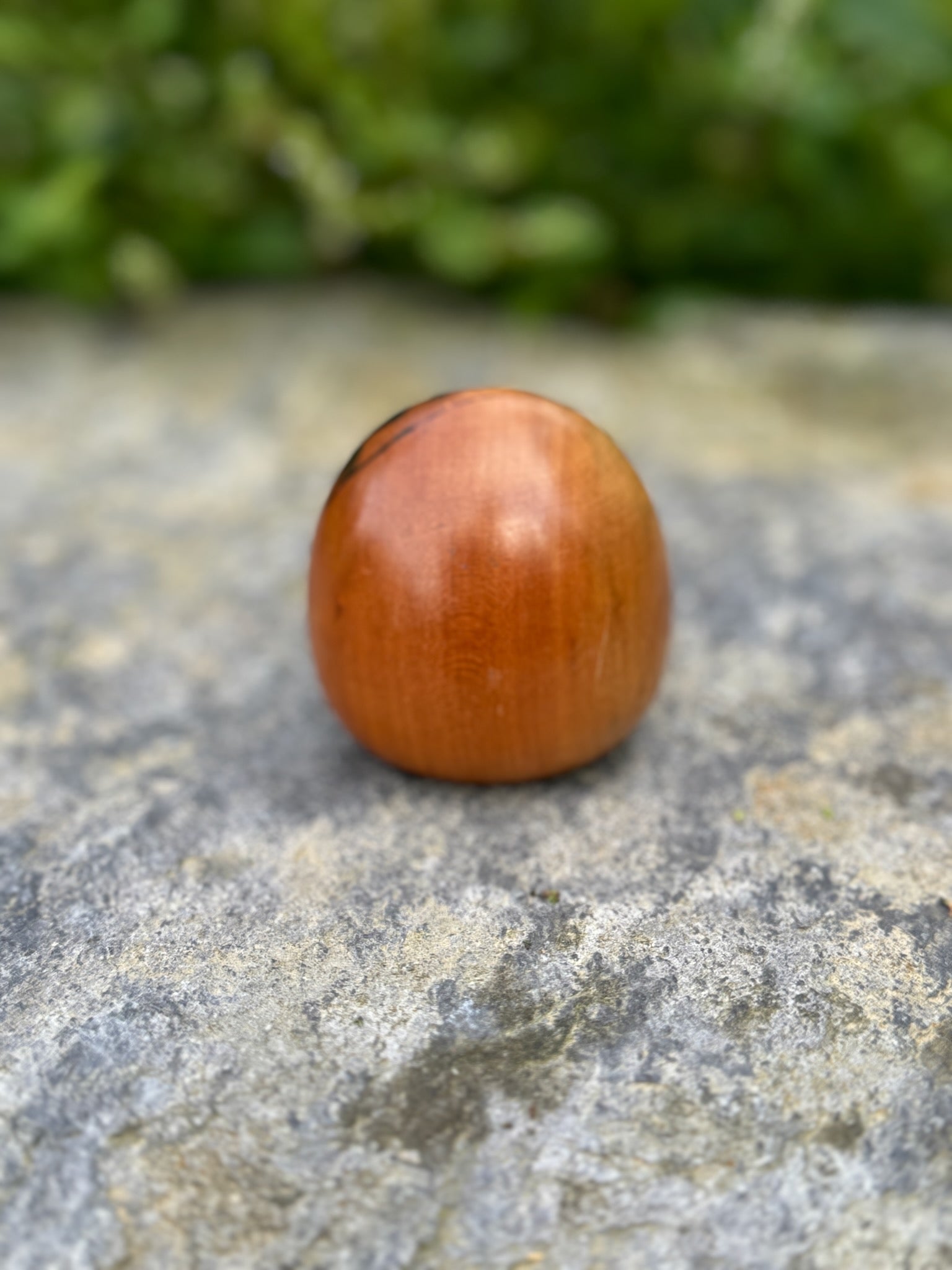 Poupée daruma en bois de forme ronde avec des détails peints noirs et rouges et un caractère japonais sur le devant vue de dos
