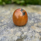 Poupée daruma en bois de forme ronde avec des détails peints noirs et rouges et un caractère japonais sur le devant vue de profil