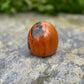 Poupée daruma en bois de forme ronde avec des détails peints noirs et rouges et un caractère japonais sur le devant vue autre profil