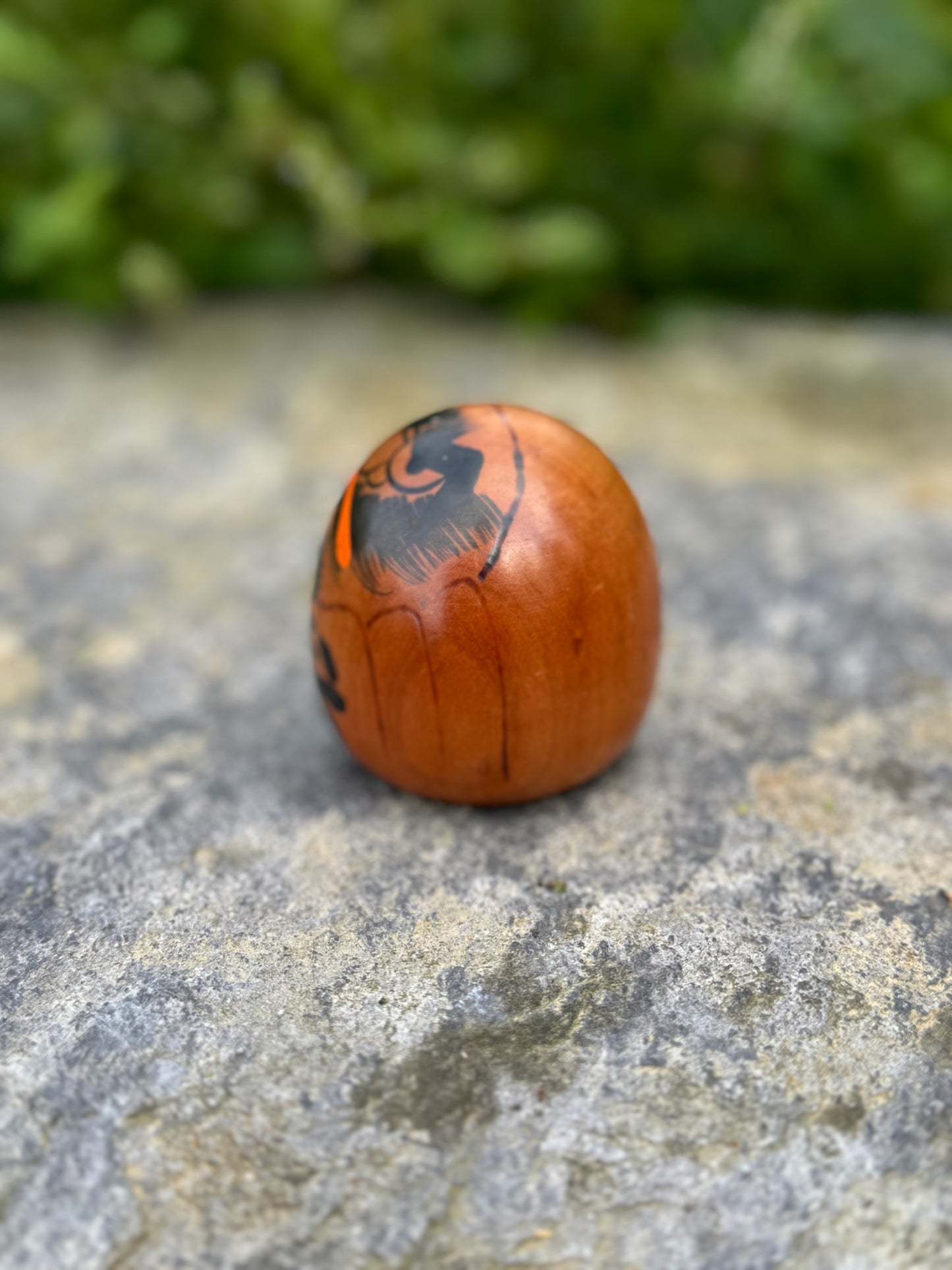 Poupée daruma en bois de forme ronde avec des détails peints noirs et rouges et un caractère japonais sur le devant vue autre profil