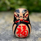 Daruma en bois blanc peint noir et rouge avec calligraphie face