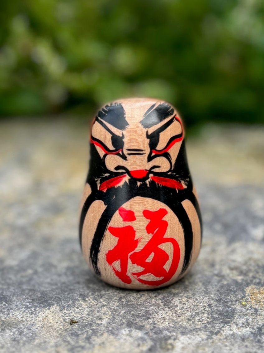 Daruma en bois blanc peint noir et rouge avec calligraphie face