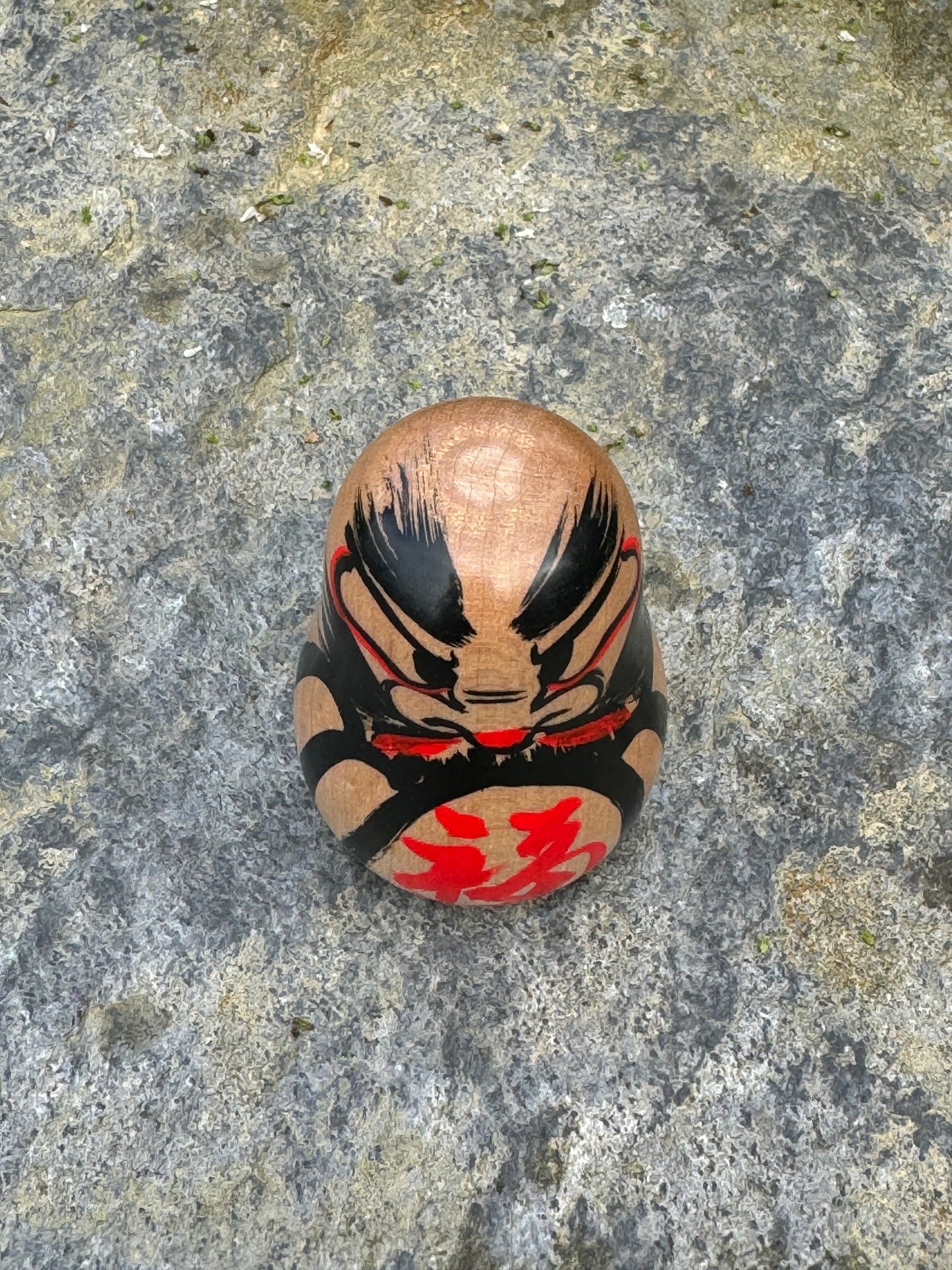 Daruma en bois blanc peint noir et rouge avec calligraphie dessus